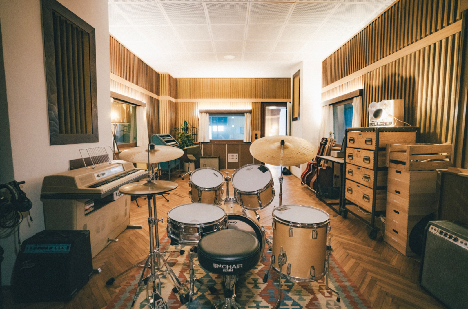 Musikzimmer mit Schlagzeug, Gitarre, Keyboard, Verstärker und Musikinstrumenten im Hintergrund.