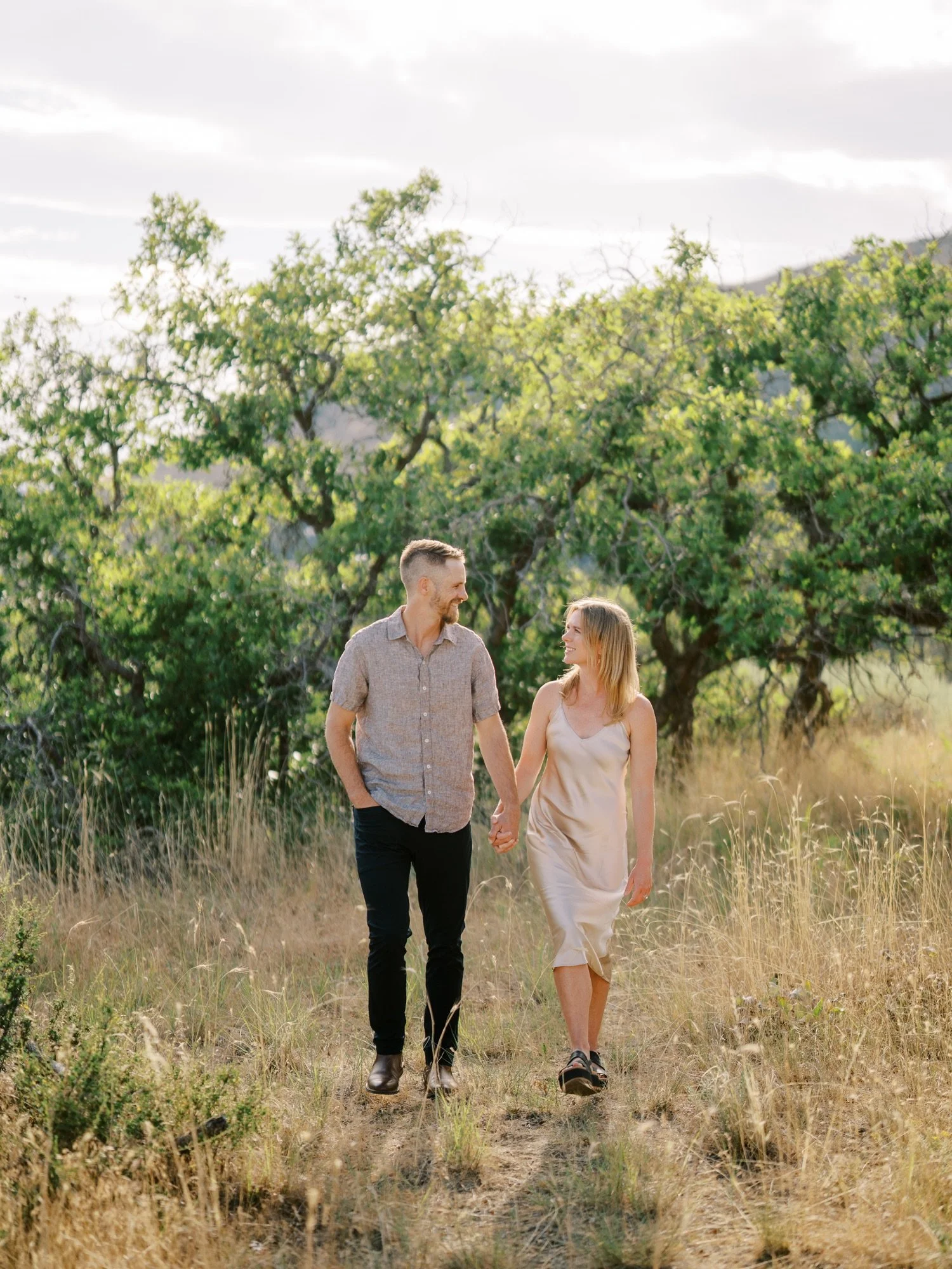 Couple walking hand in hand through tall grass