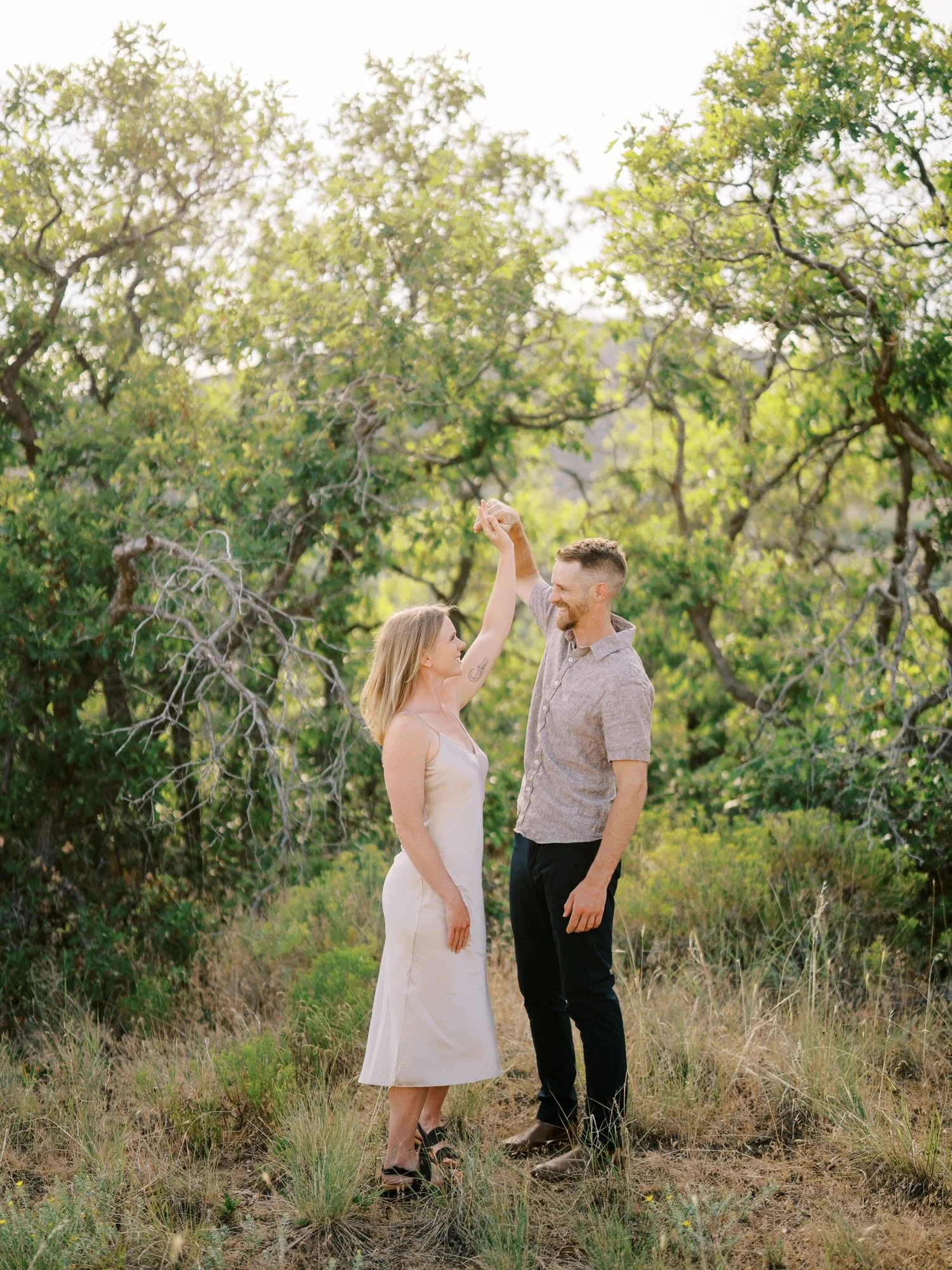 Couple facing each other beside sunlit trees