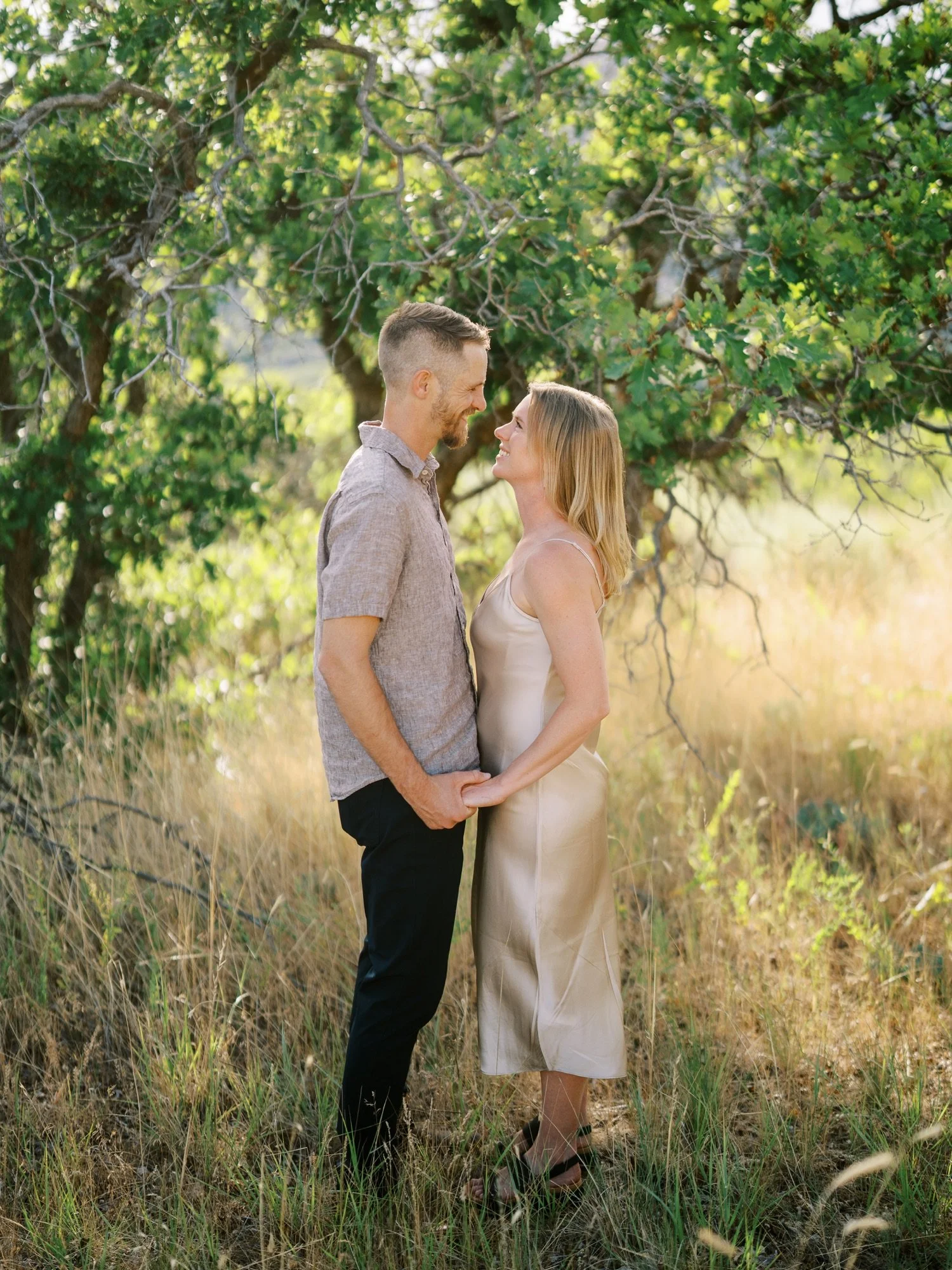 Couple sharing a kiss beneath green branches