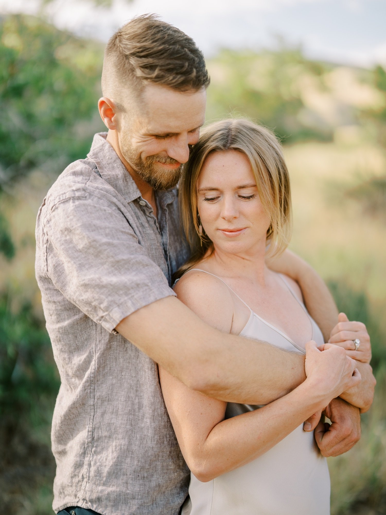 Man embracing his fiancée from behind in a summer field