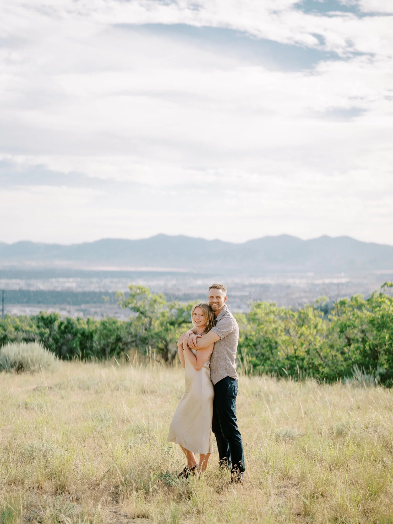 Wide portrait of a couple embracing with distant mountains behind them