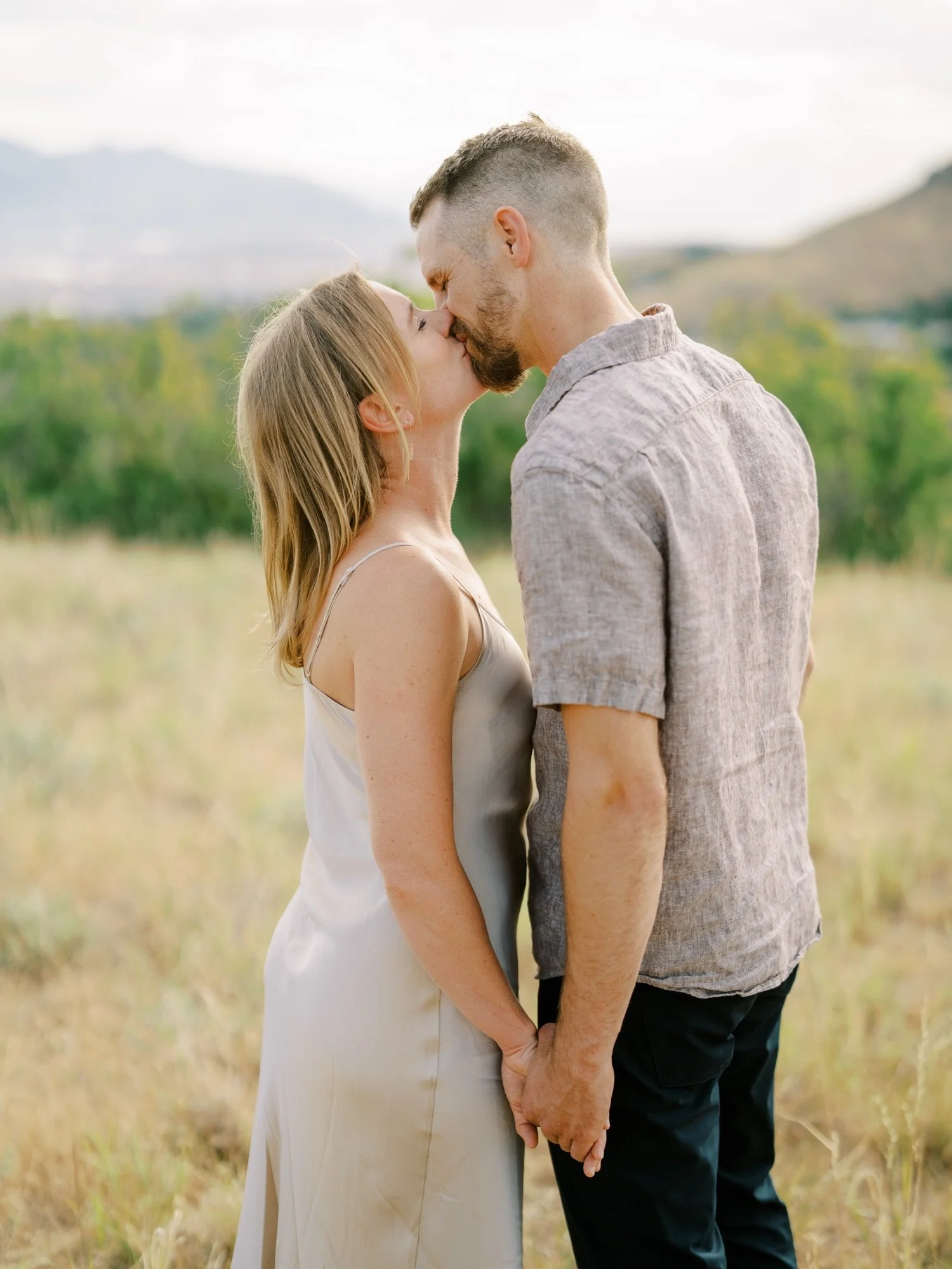Couple kissing in tall grass during their engagement session