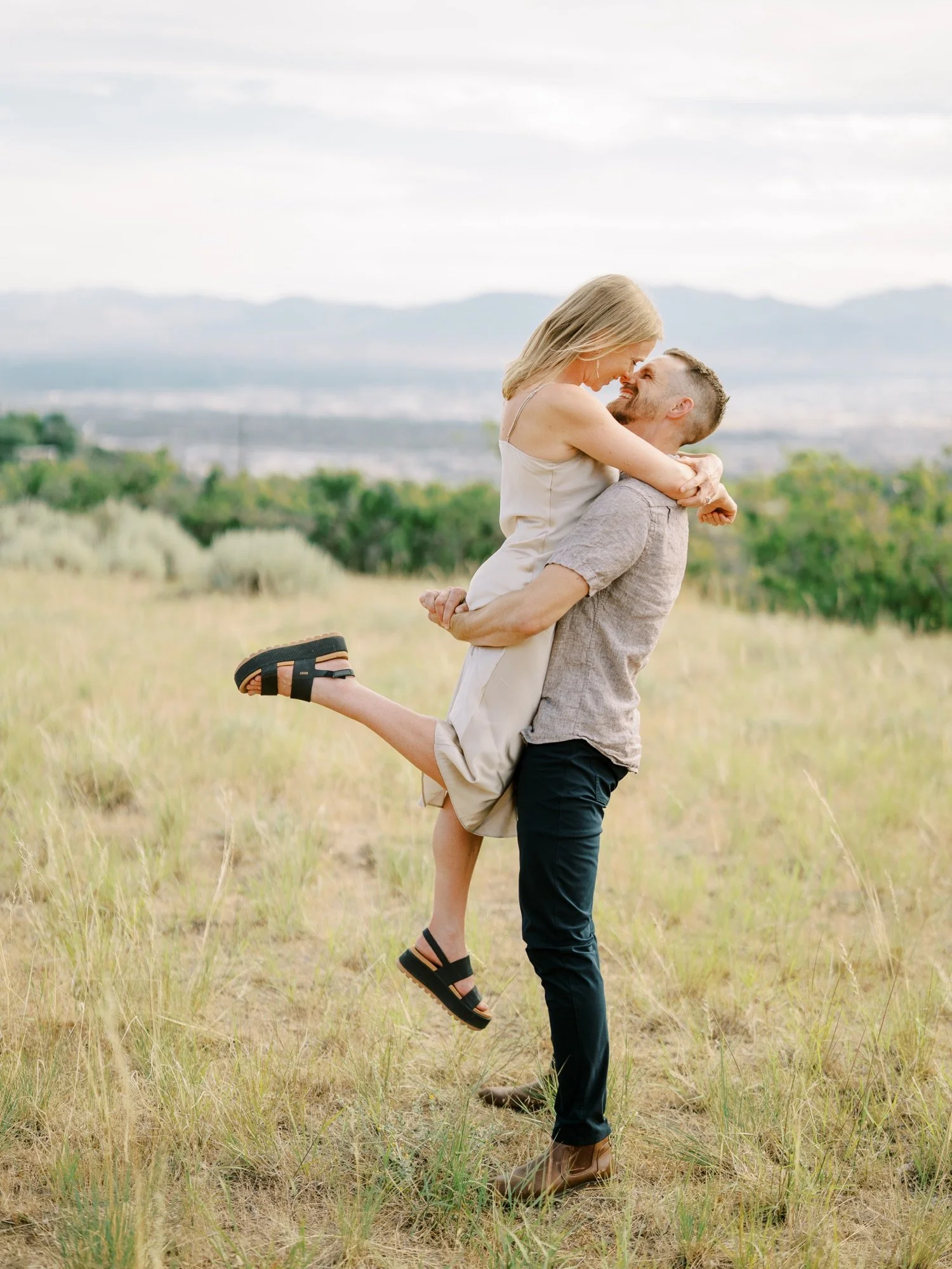 Man lifting his fiancée in a Northern Utah field