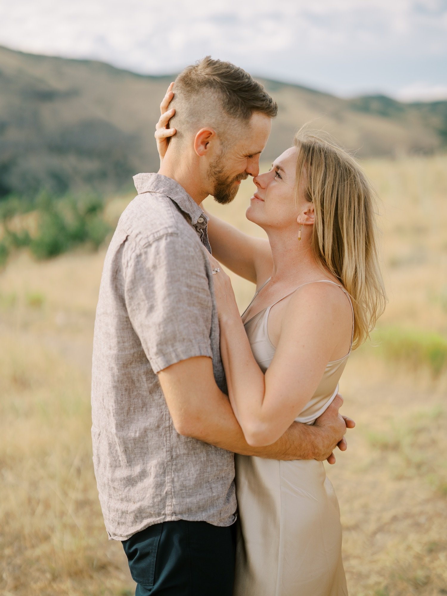 Close portrait of a couple leaning toward each other in a meadow