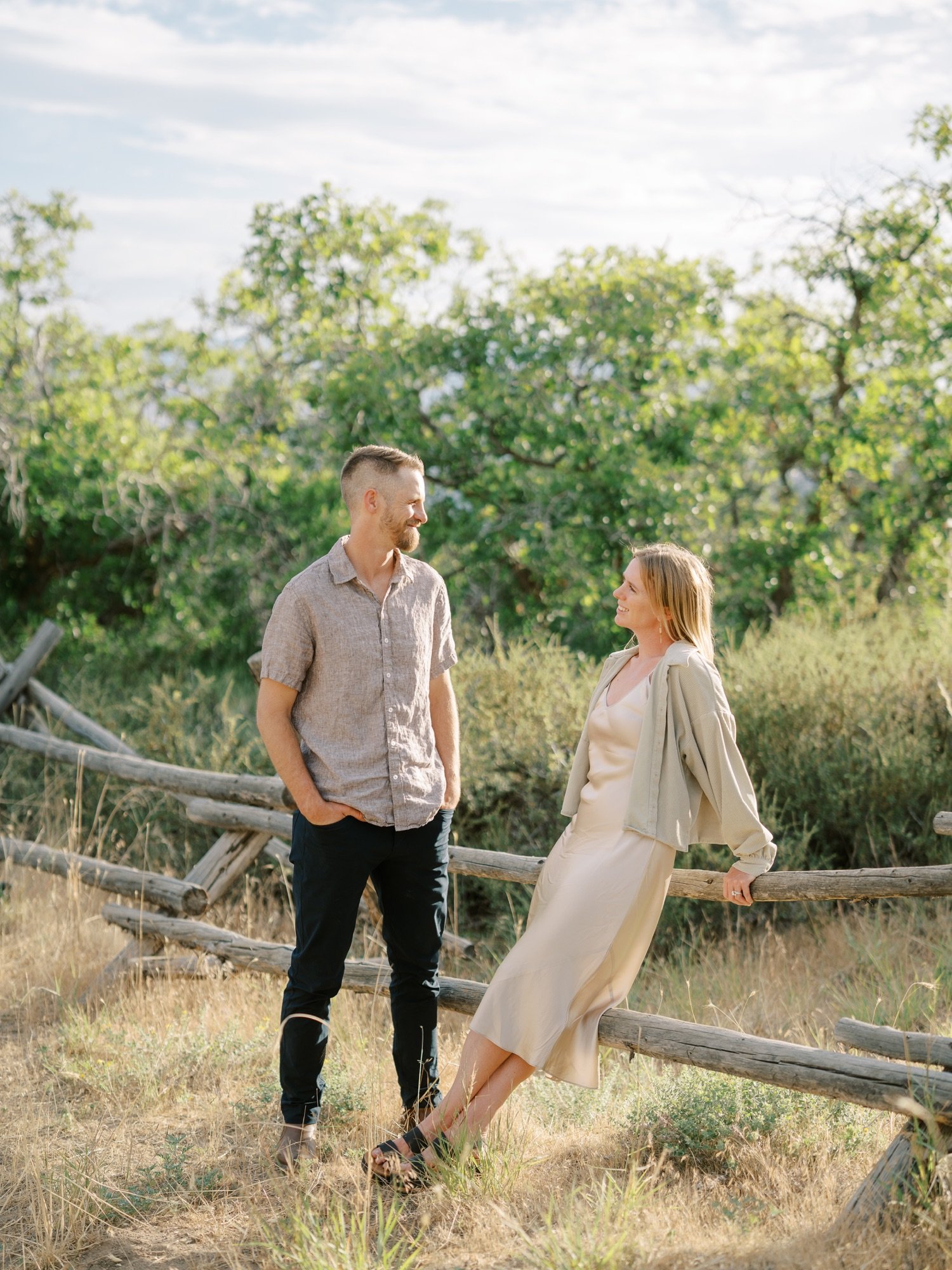 Couple standing beside a rustic wooden fence