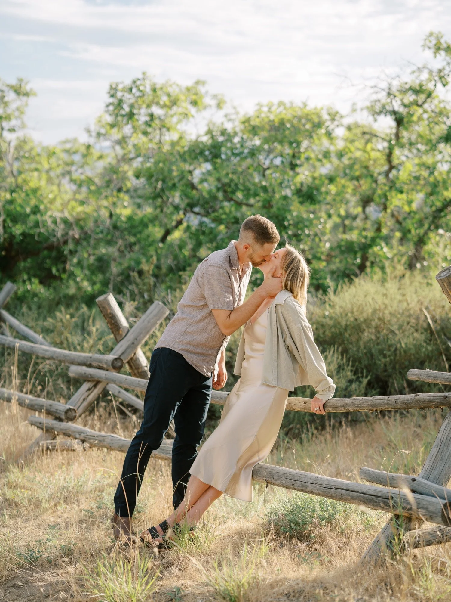 Couple sharing a kiss beside a wooden fence in Northern Utah