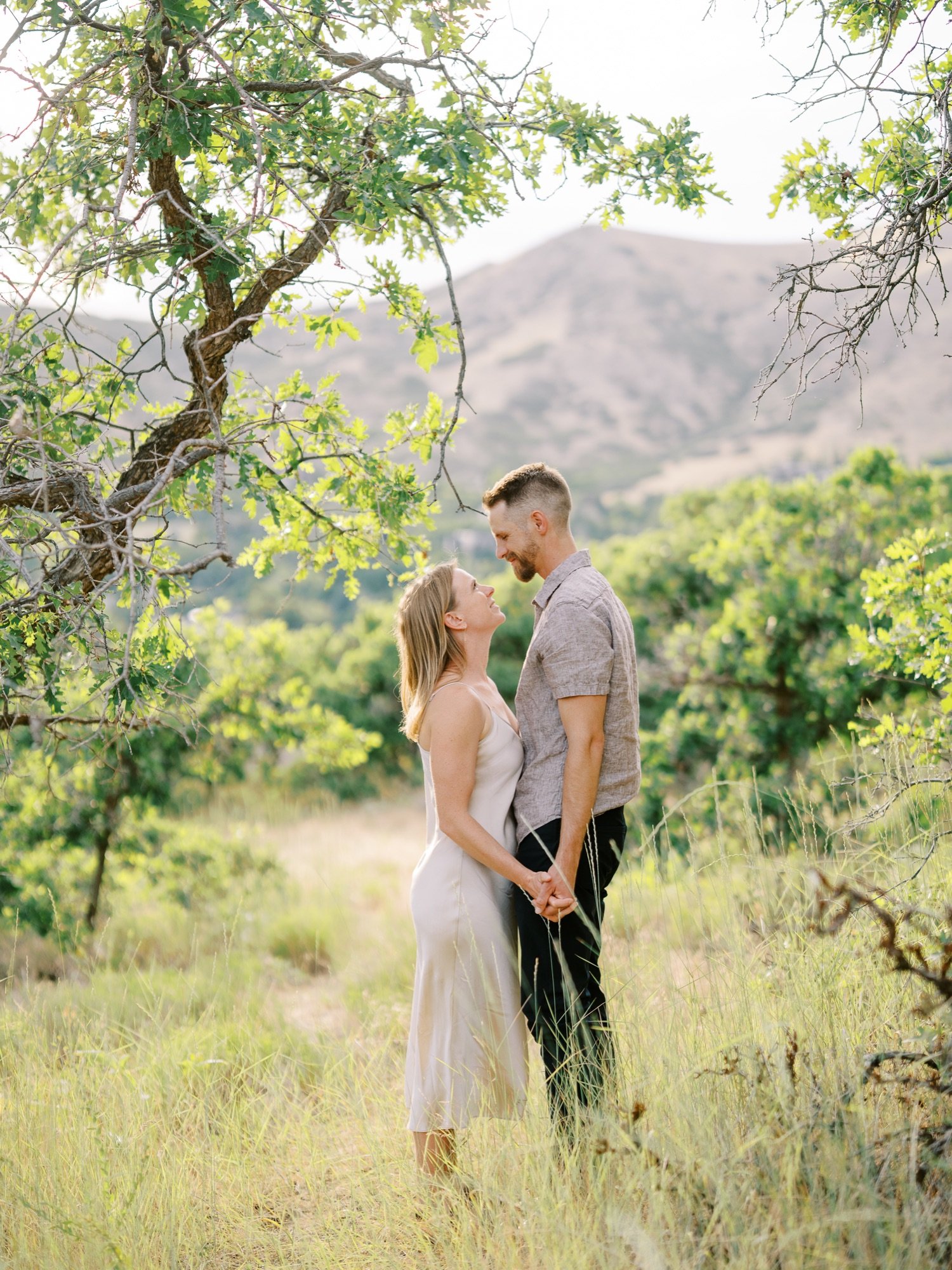 Couple embracing beneath a tree with mountains in the background
