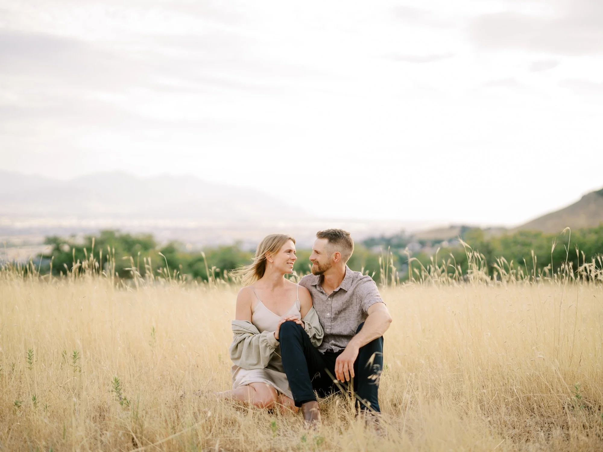 Engaged couple sitting together in tall golden grass