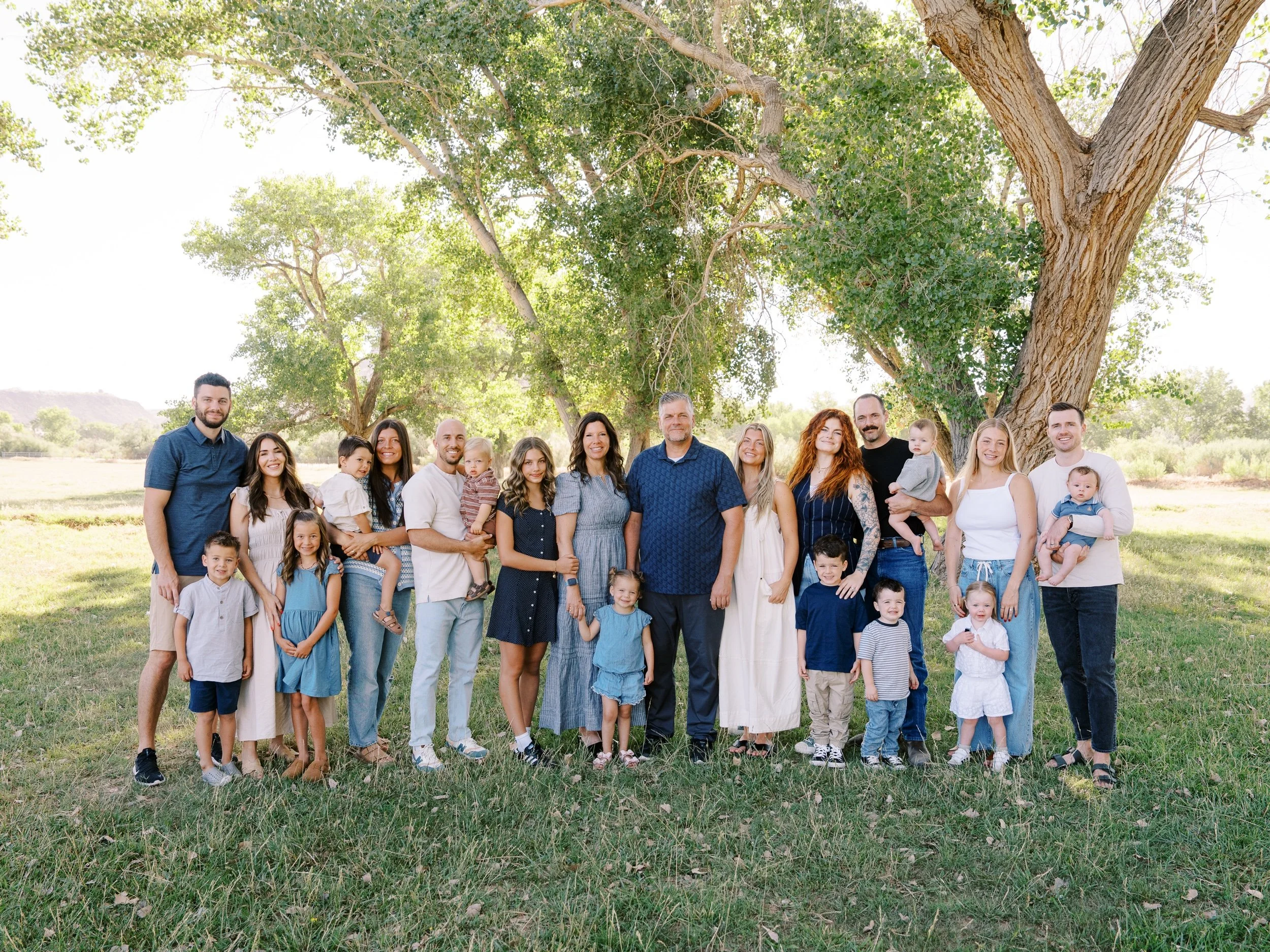 Extended family standing together beneath a large tree at Kirkland Fields in Washington, Utah.