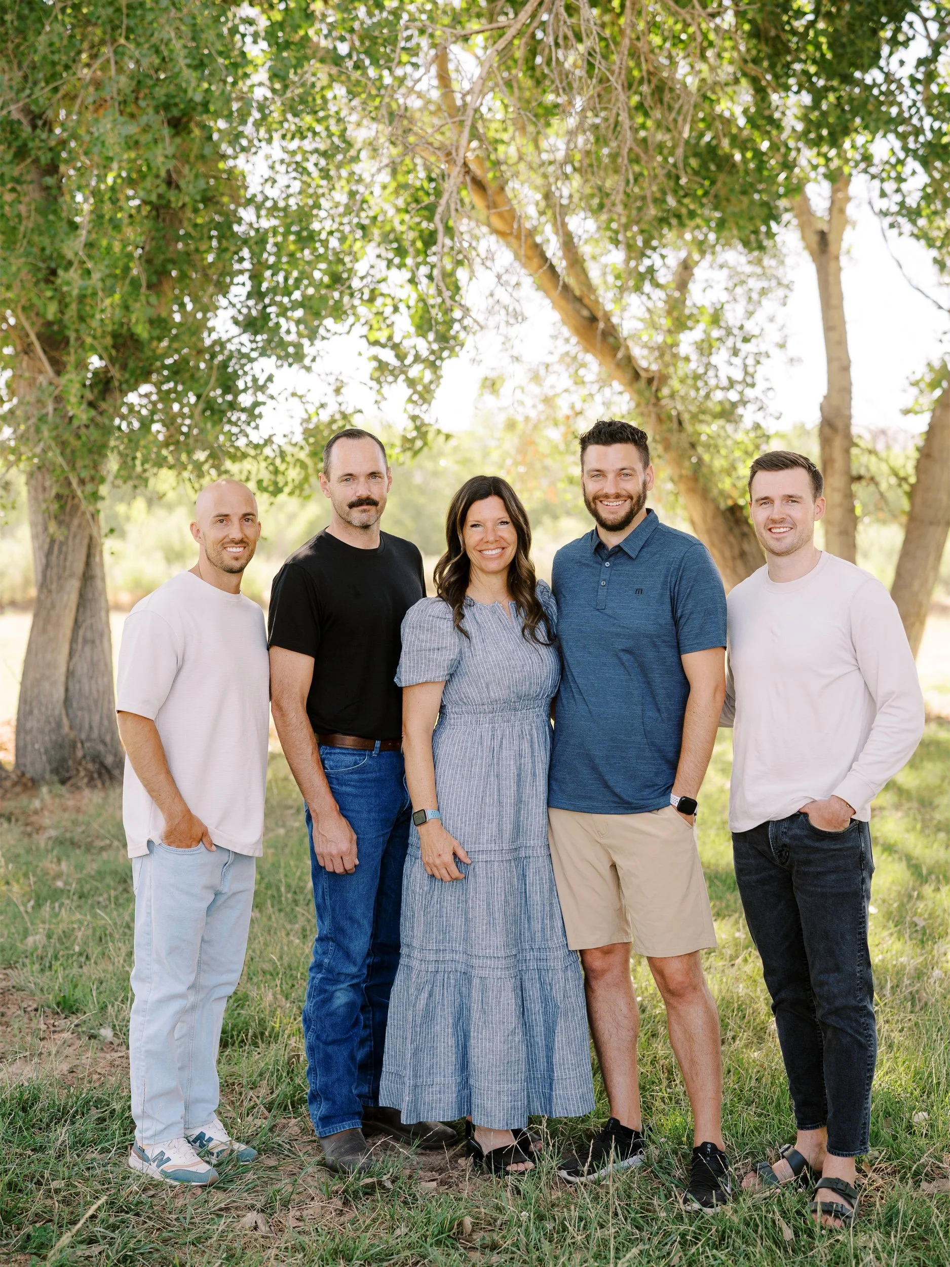 A woman standing with four men on the grass.