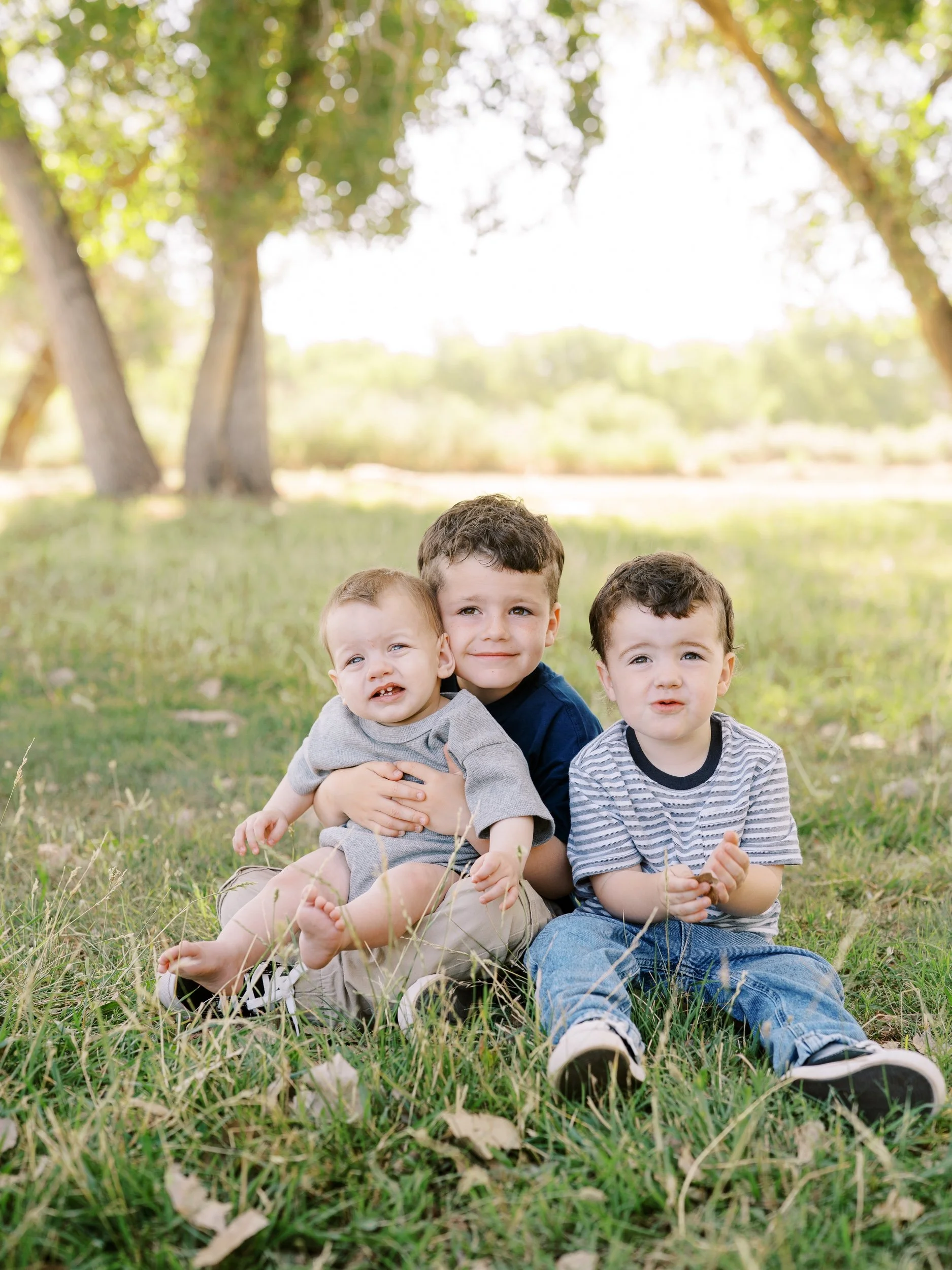 Three brothers sitting together on the grass.
