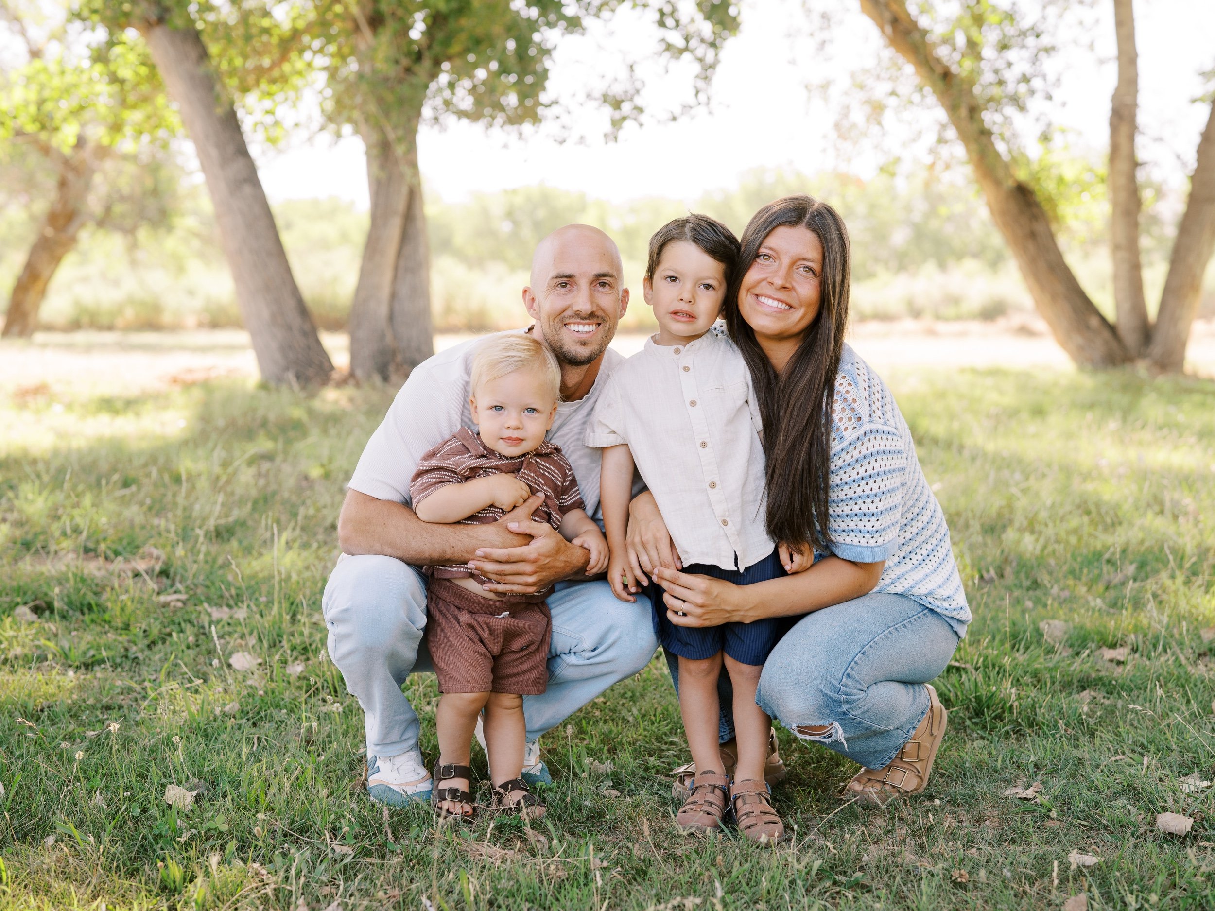 Parents crouching beside their two young children.
