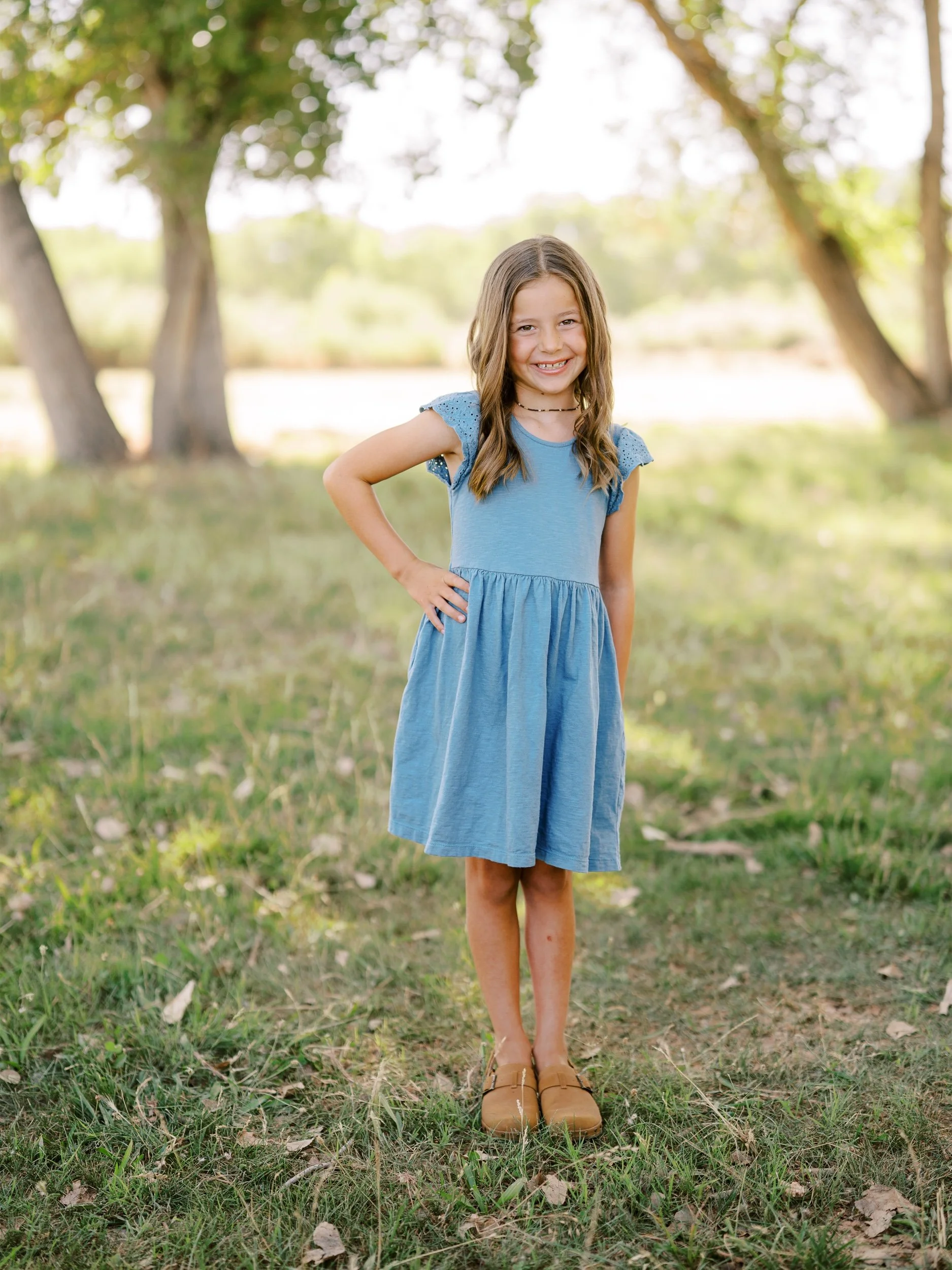 A girl in a blue dress with her hand on her hip.