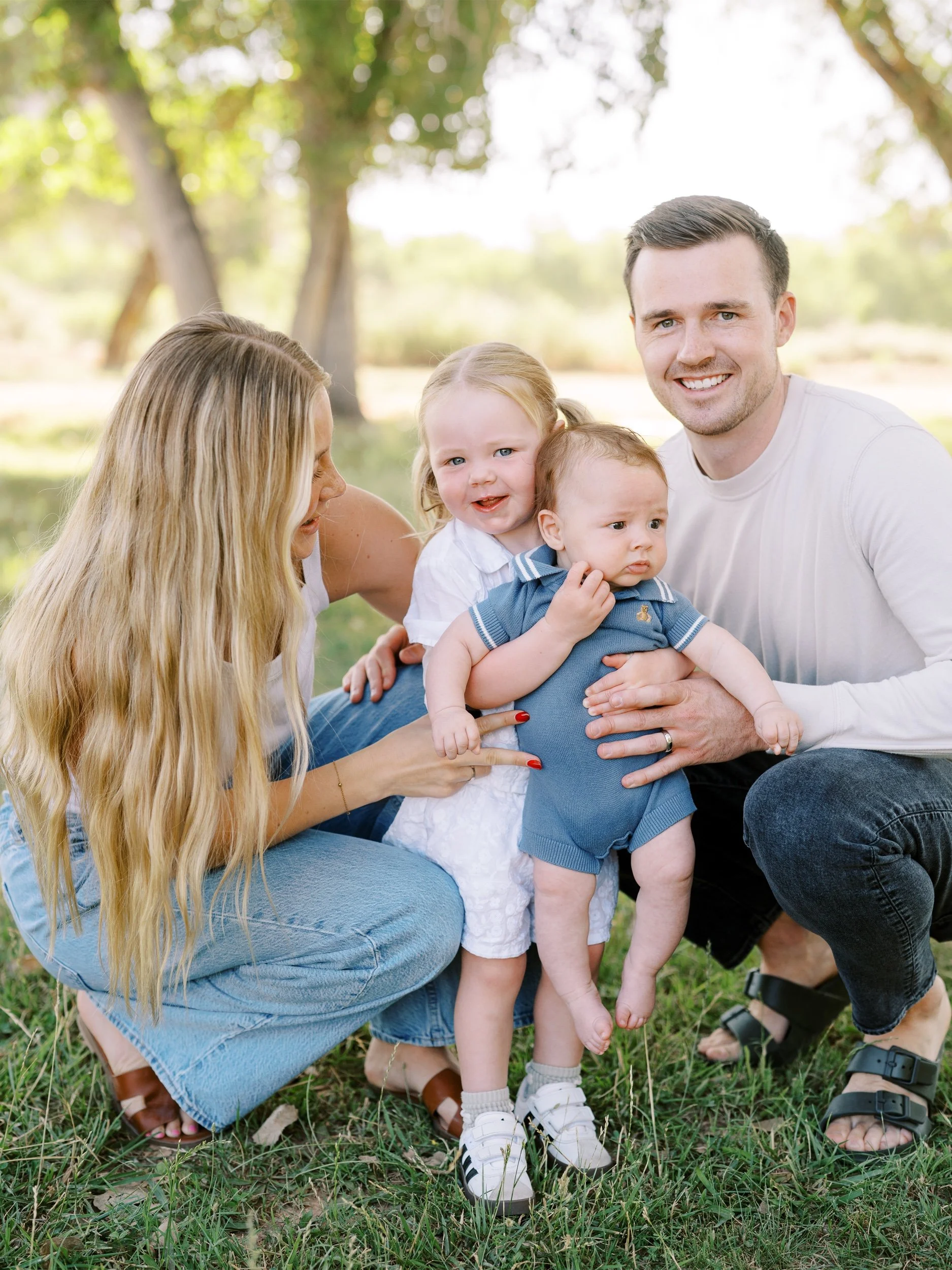 Parents crouching close to their two smiling children.