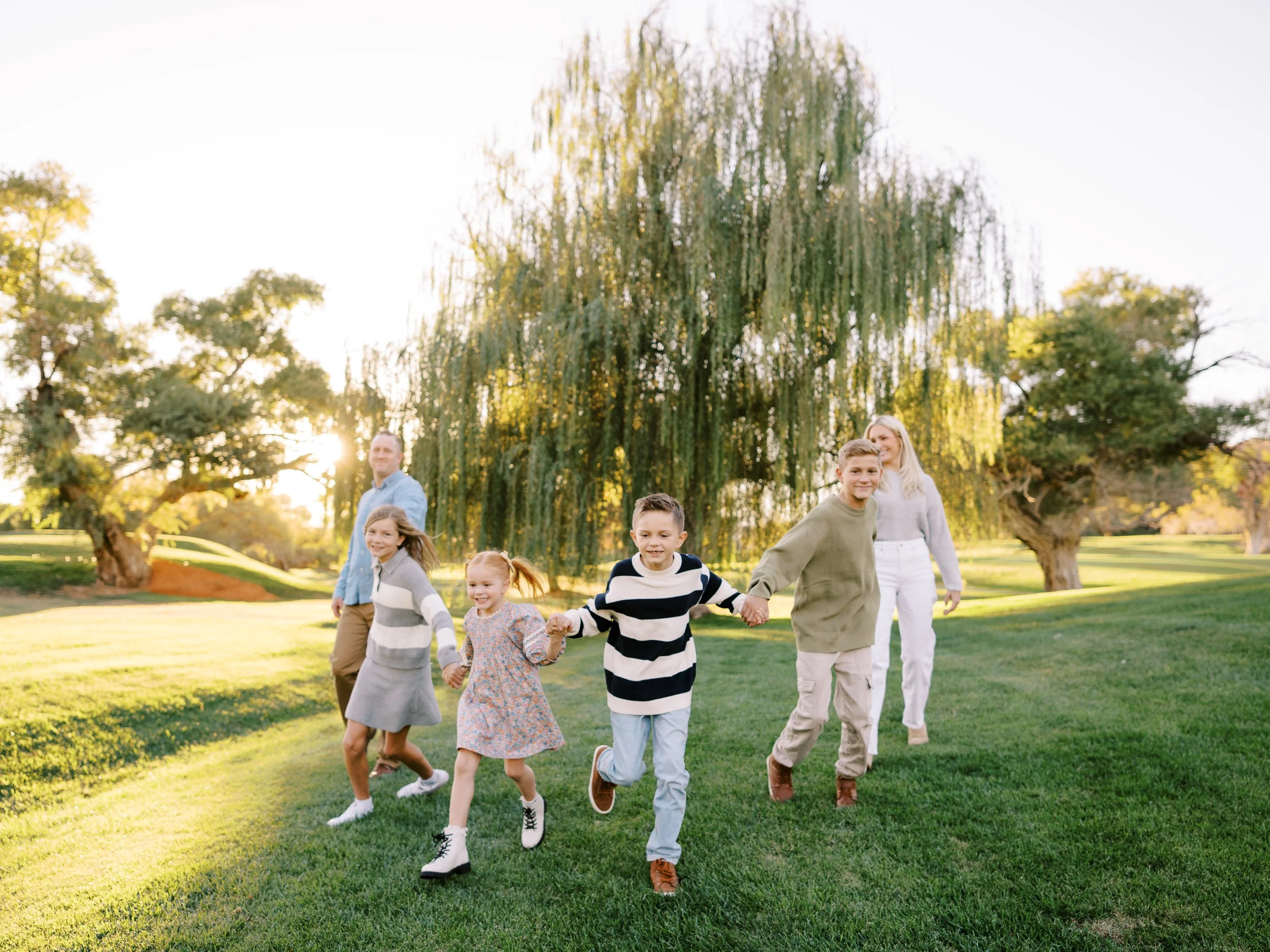 Children running forward hand in hand with their parents in the evening light