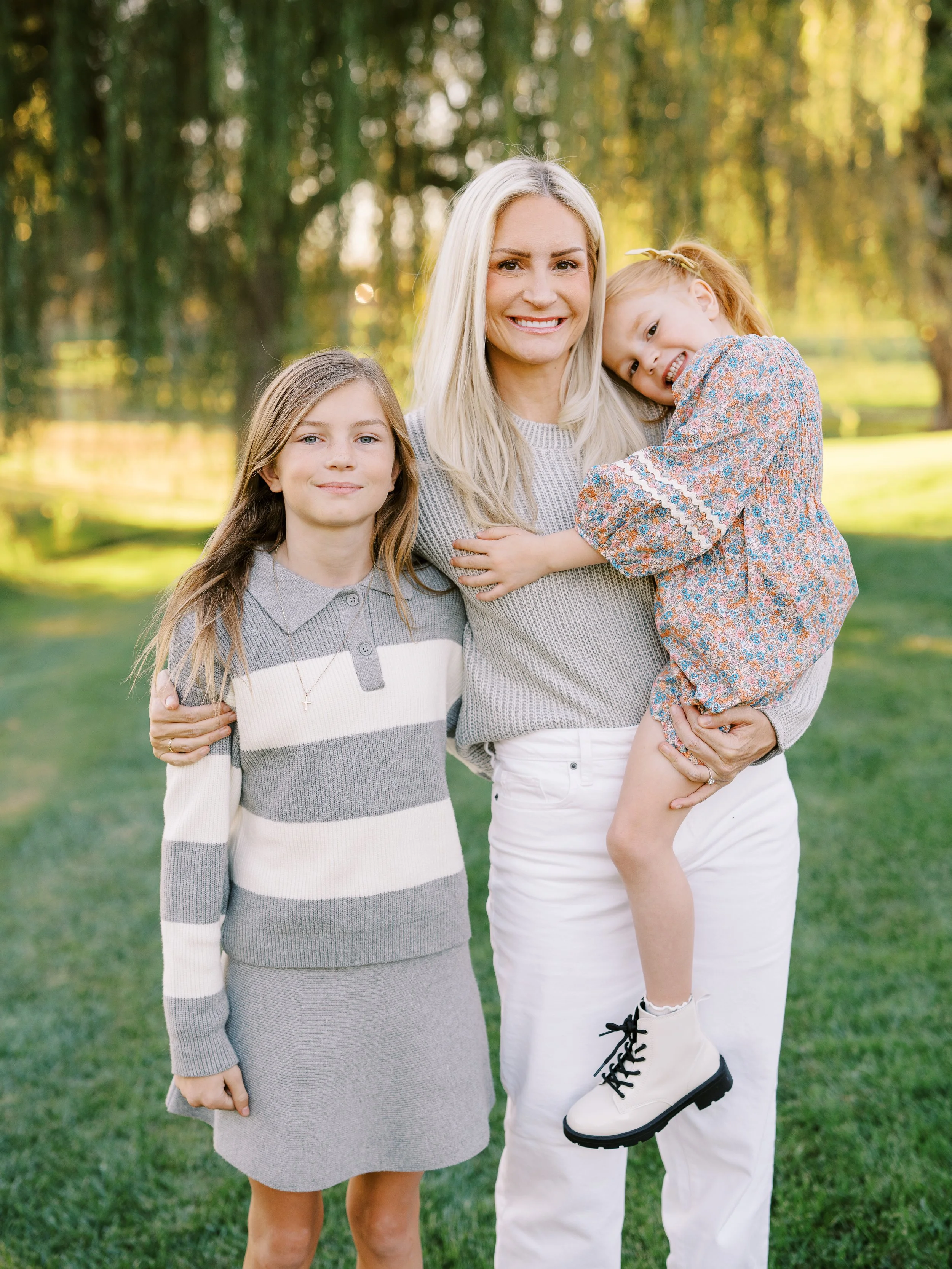 Mother holding her younger daughter close with her older daughter beside her
