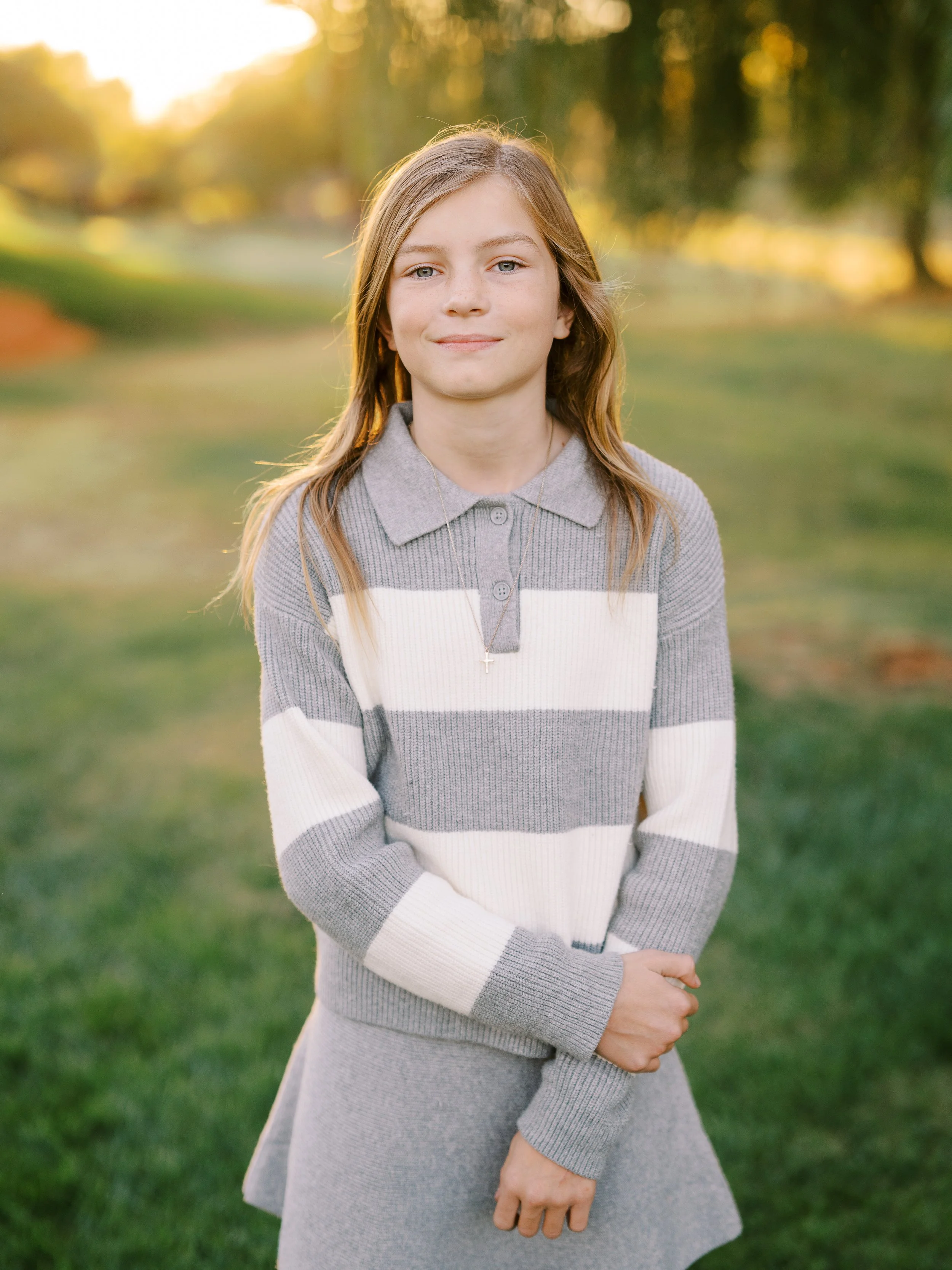 Portrait of a girl in a striped dress with her hands together
