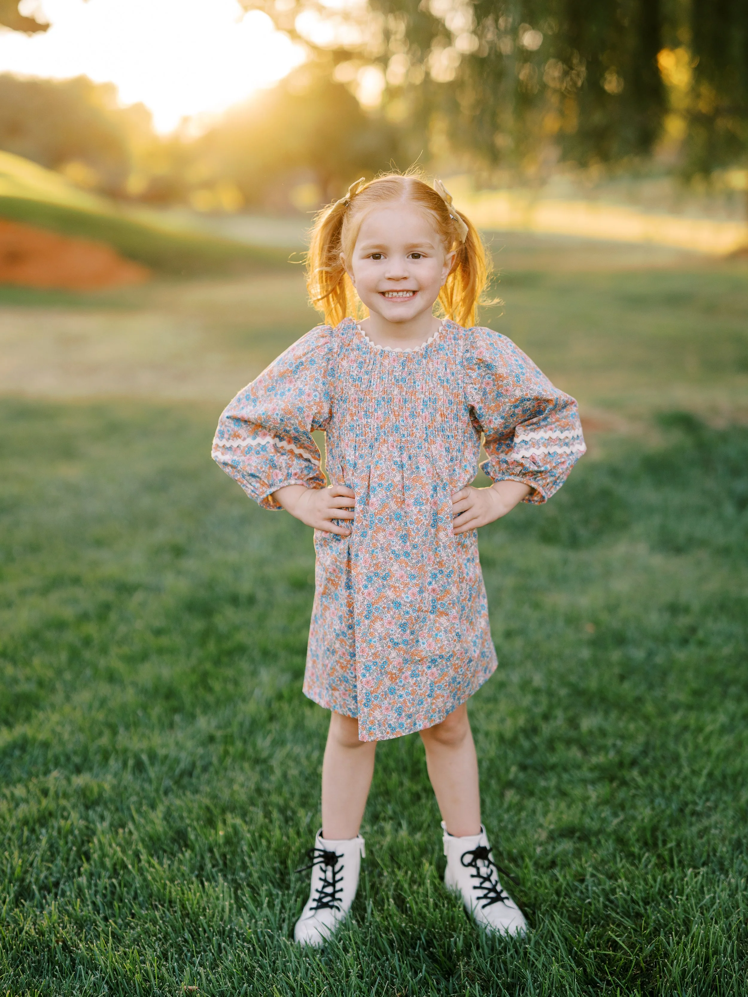 Young girl in a floral dress standing with her hands on her hips