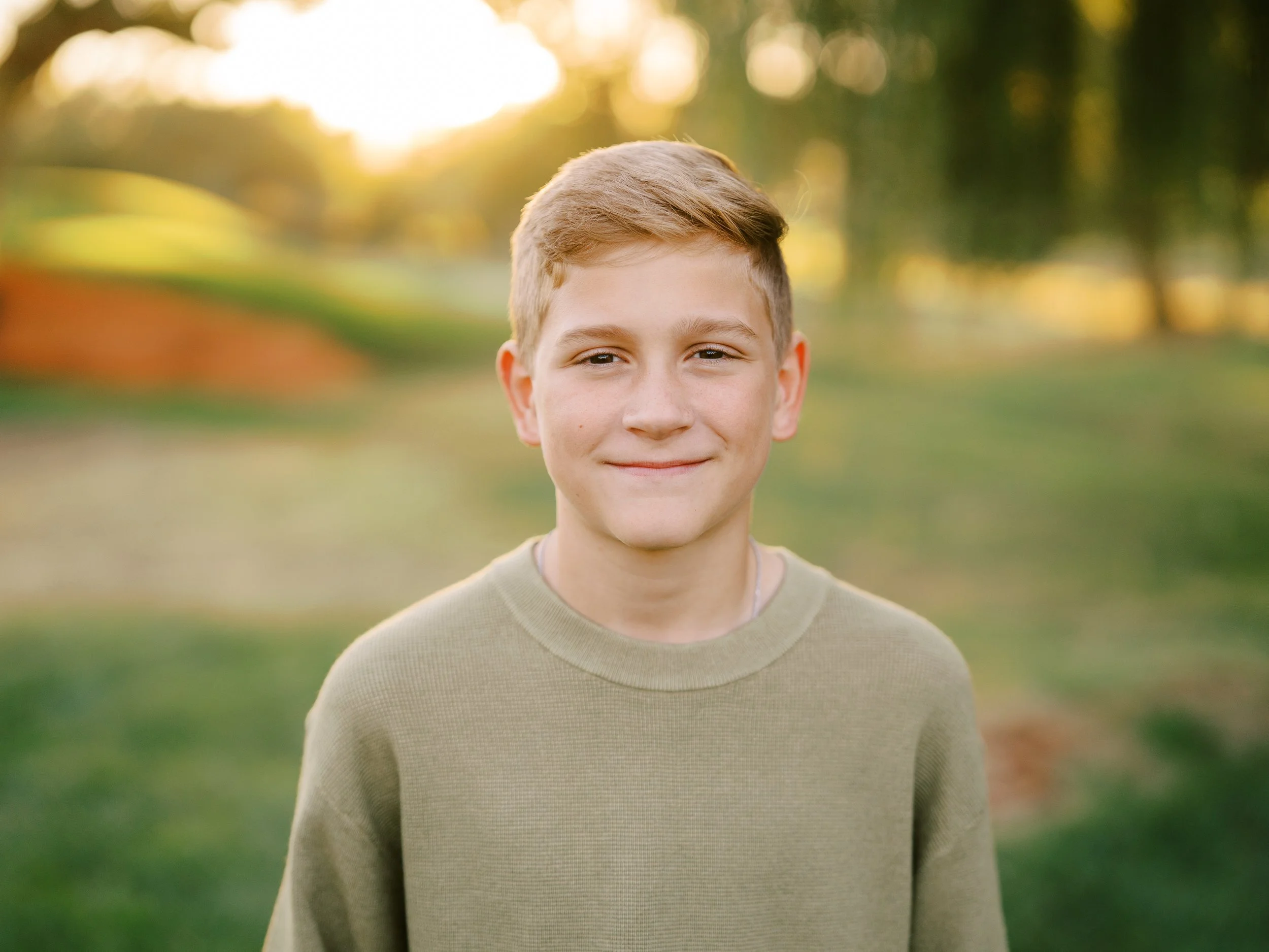 Close portrait of a smiling boy against softly blurred greenery