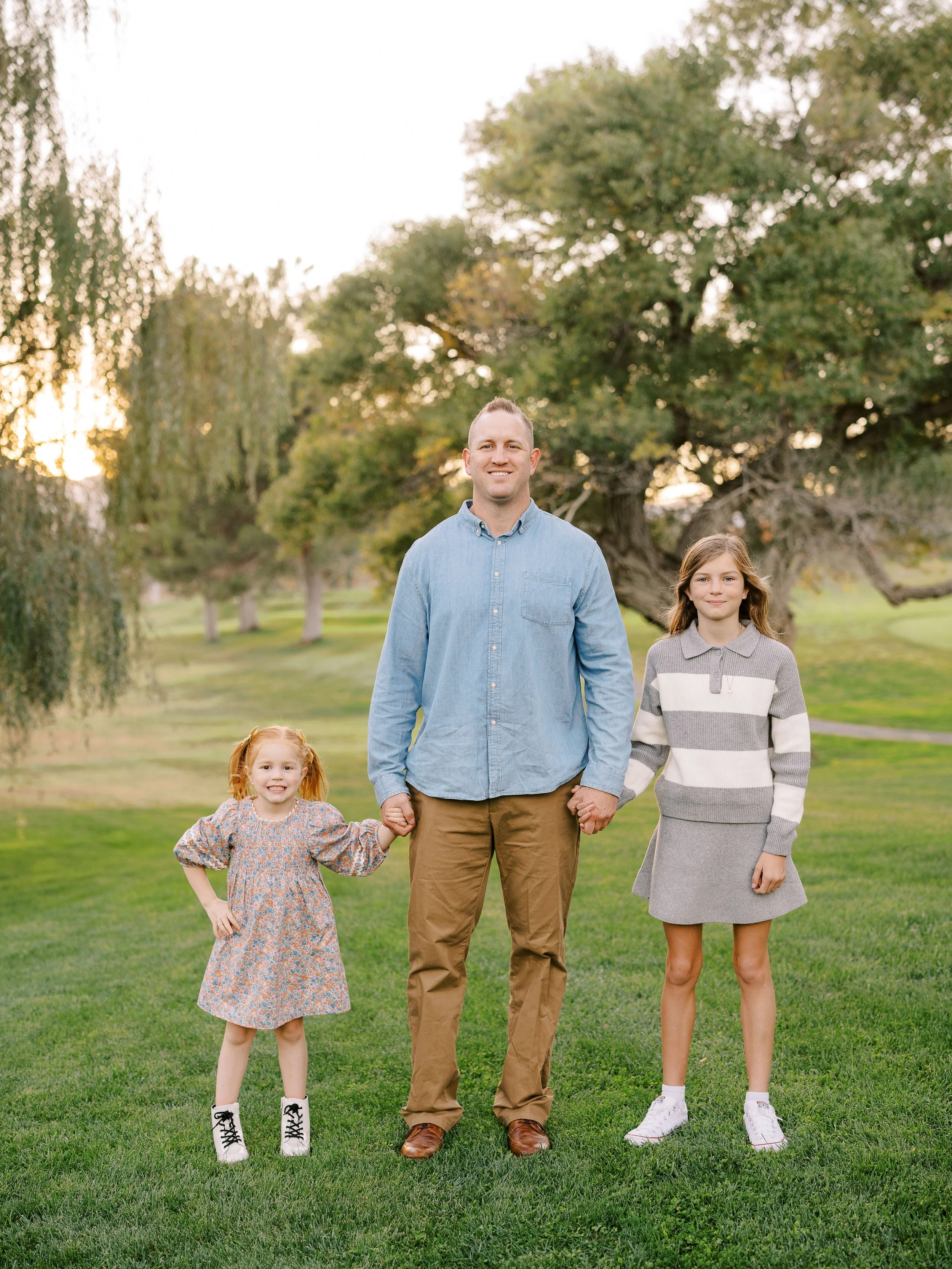 Father holding hands with his two daughters on the grass