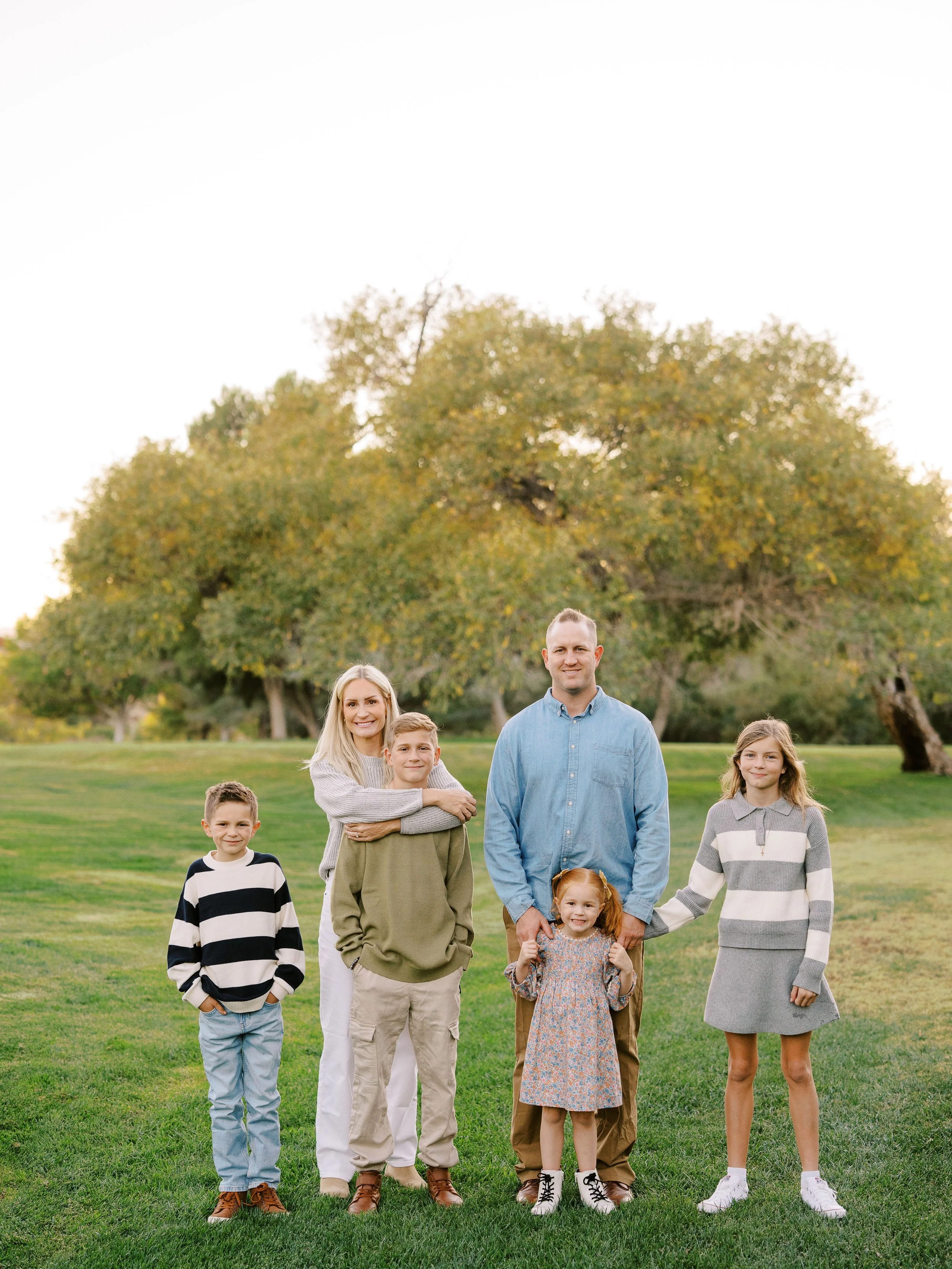 Family standing together in front of a leafy tree in the evening light