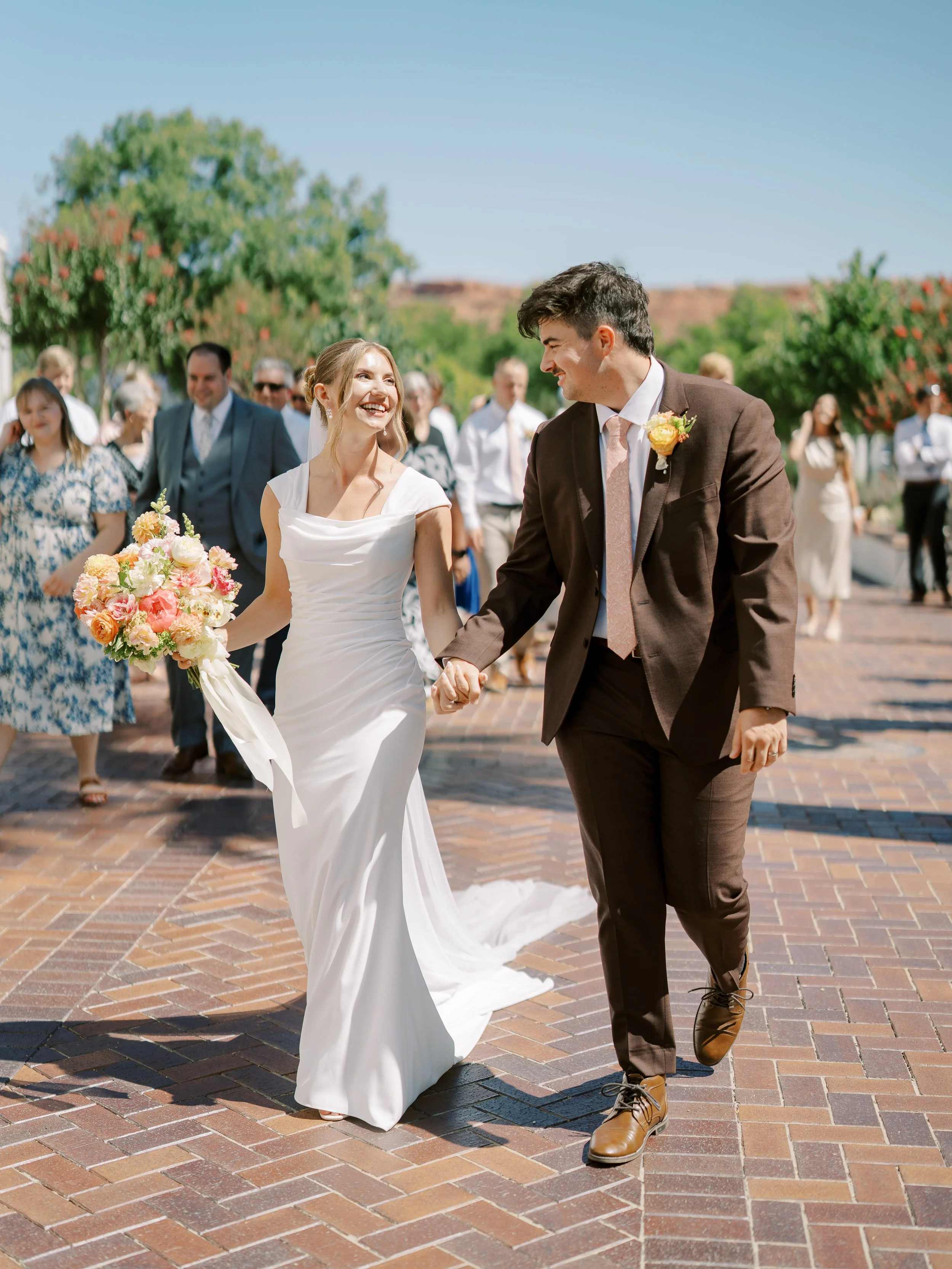 Abby and Noah smiling together with wedding guests behind them