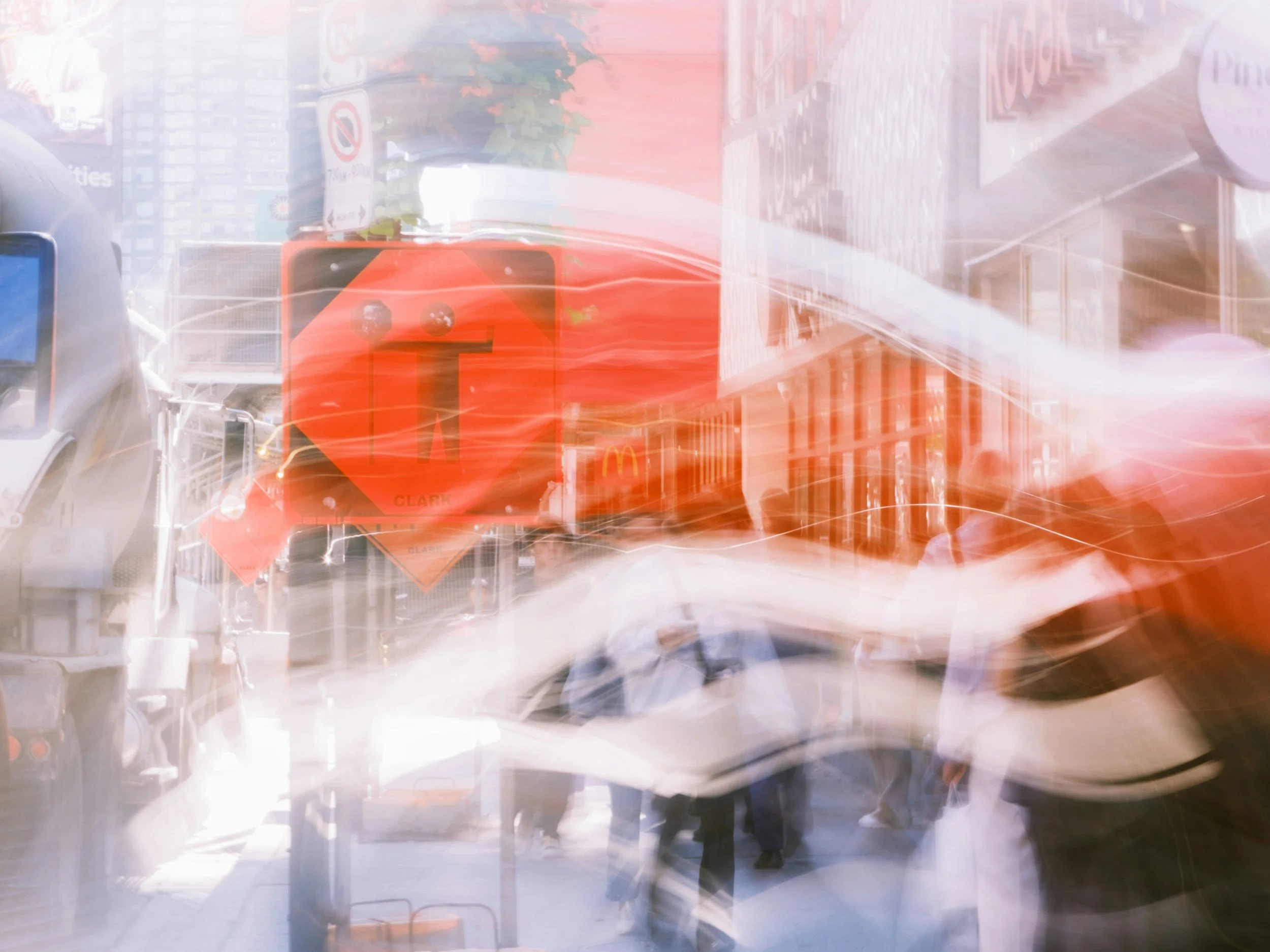 Blurred city street scene with traffic signs, a red road work sign, cars, and pedestrians.