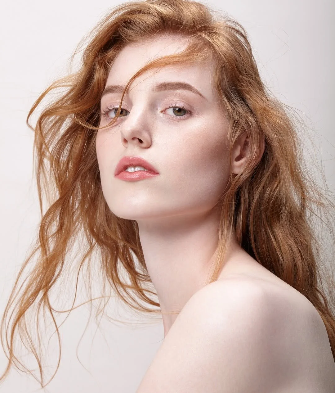 Femme appliquant de la crème sur la joue dans un contexte de soin de la peau pour la marque de maquillage 1944 Paris. 