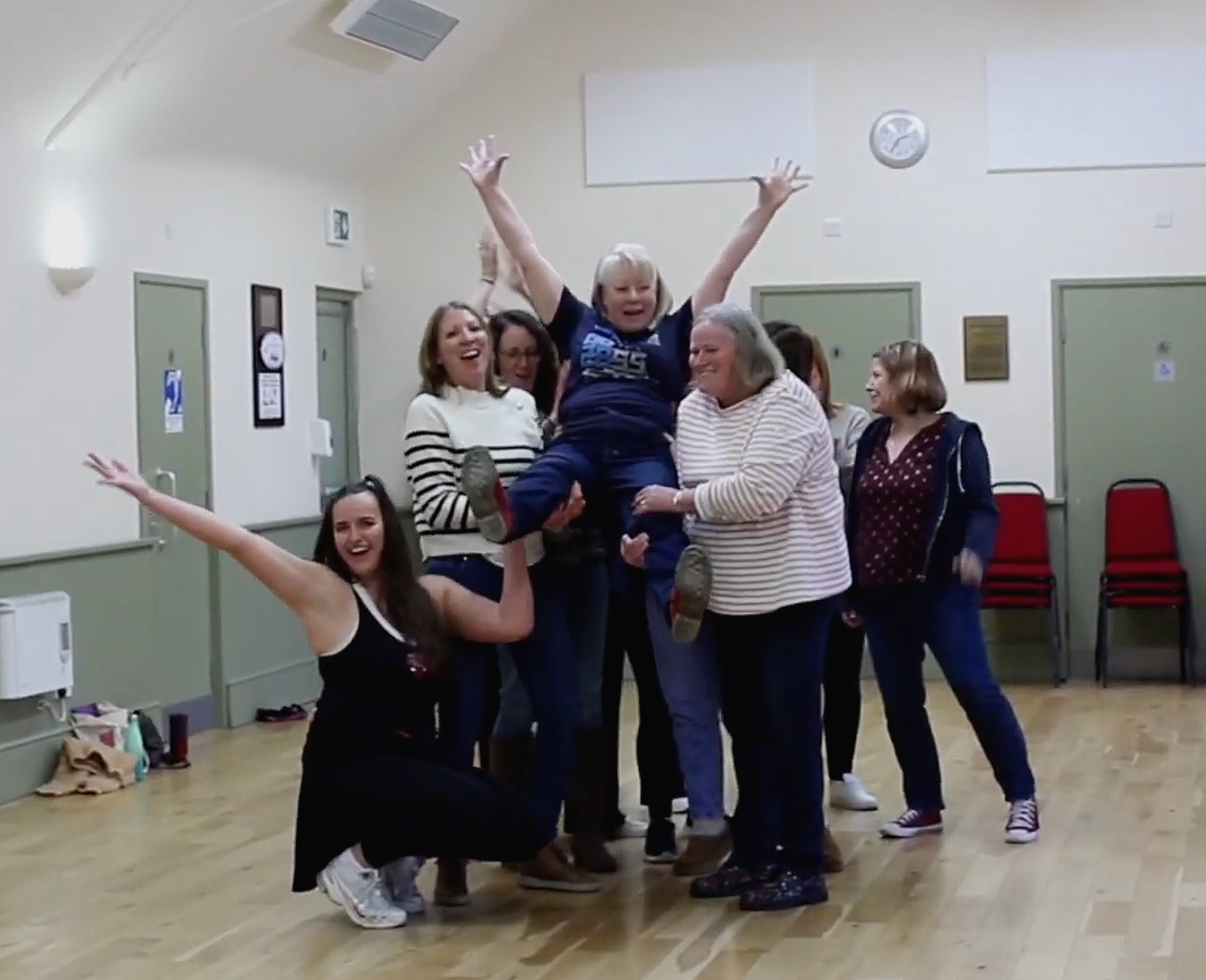 Corporate wellbeing day line dancing class with Dazzle Dance Experience group of women celebrating with lift at the end