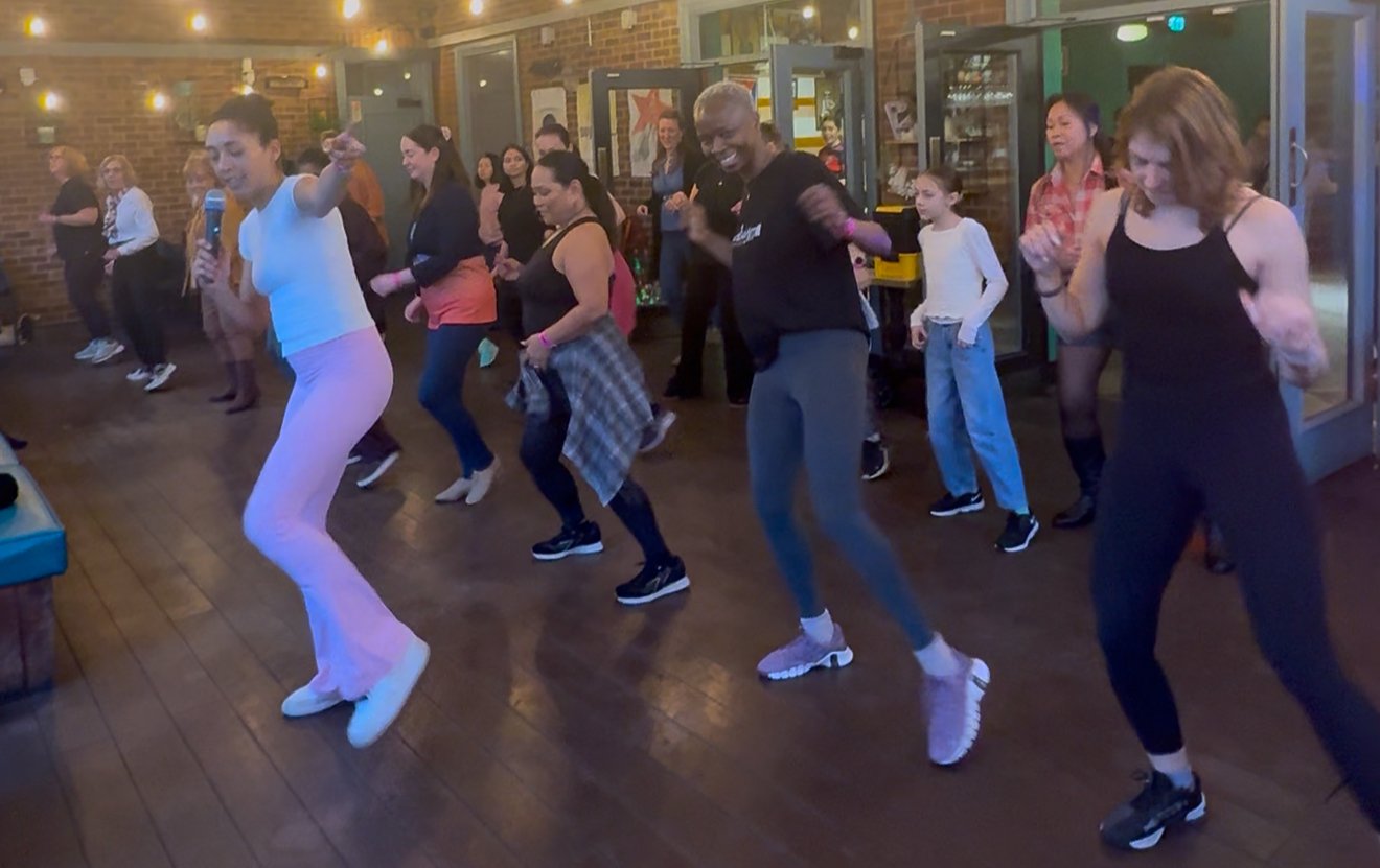 Group of people dancing indoors at a party or social event.