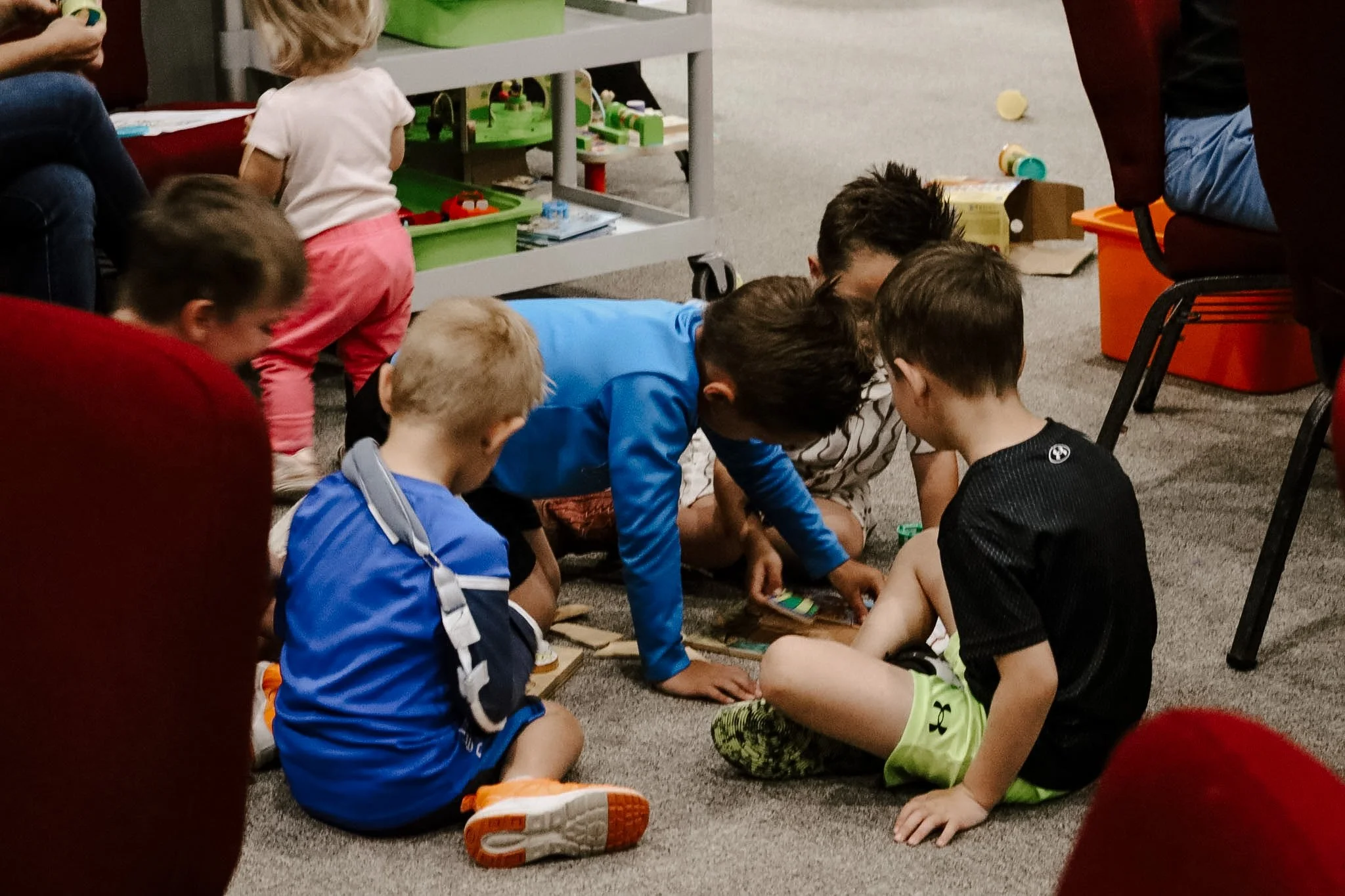 Children playing and working together on the floor during a group activity, with toys and books around in a room.