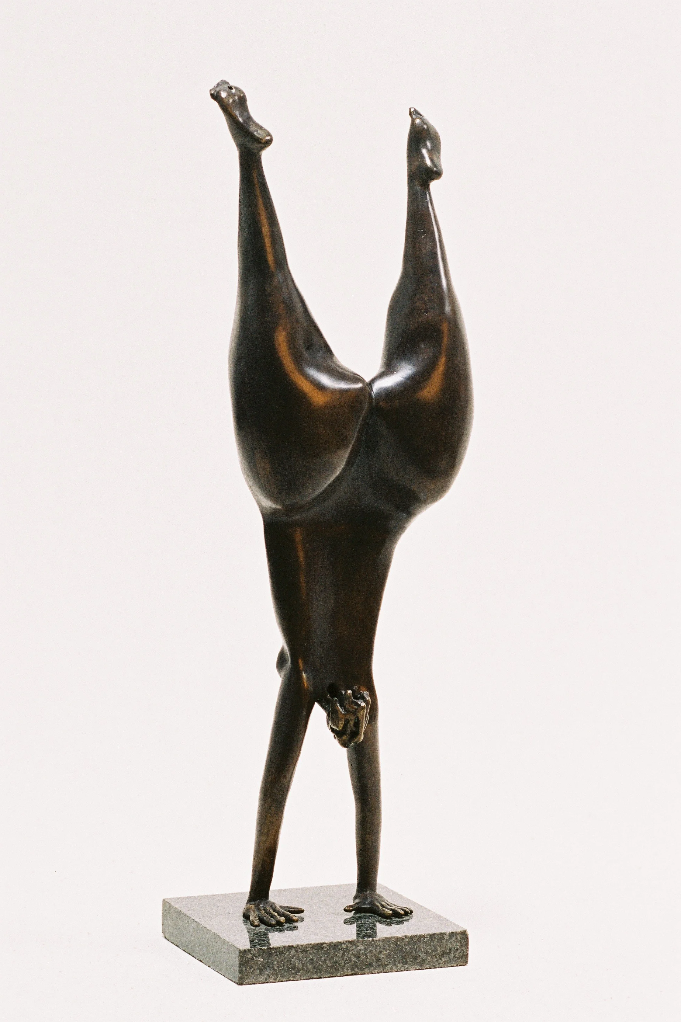 Sculpture en bronze représentant une figure humaine en position acrobate, équilibrant sur la tête et les mains, avec les jambes levées en l'air.