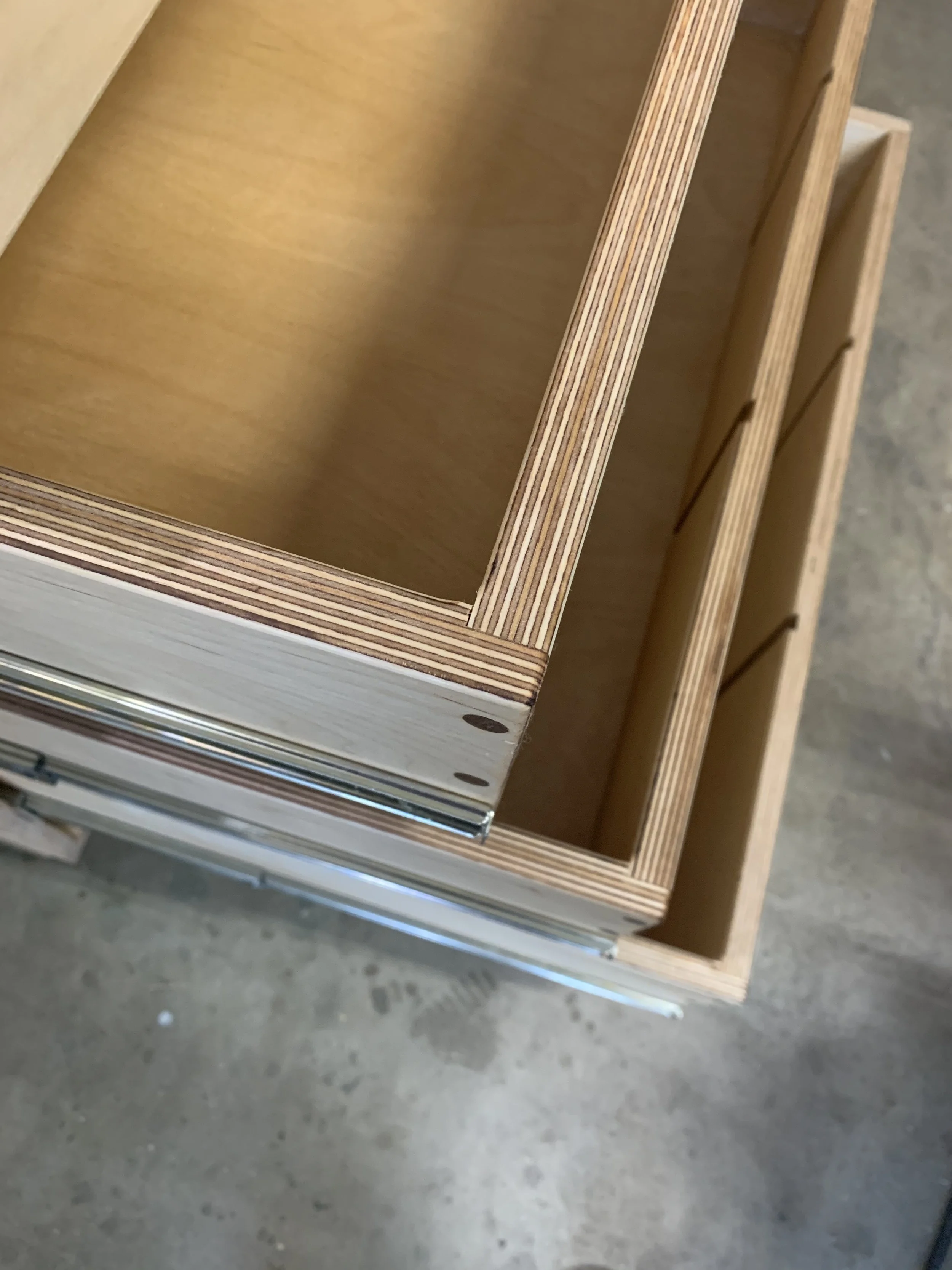 Close-up of wooden drawers with metal slides, showing inner compartments and construction details.