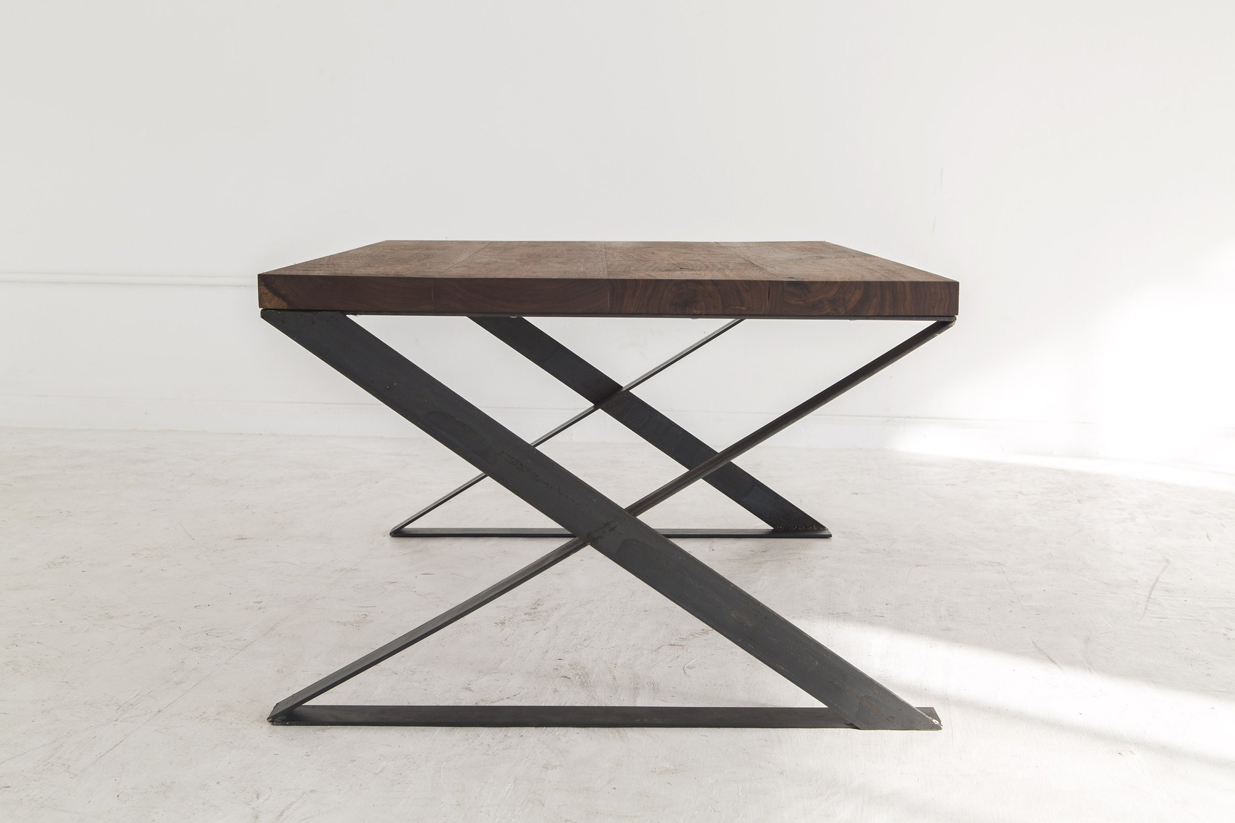 Modern side table with a wooden top and crossed metal legs on a plain white background.