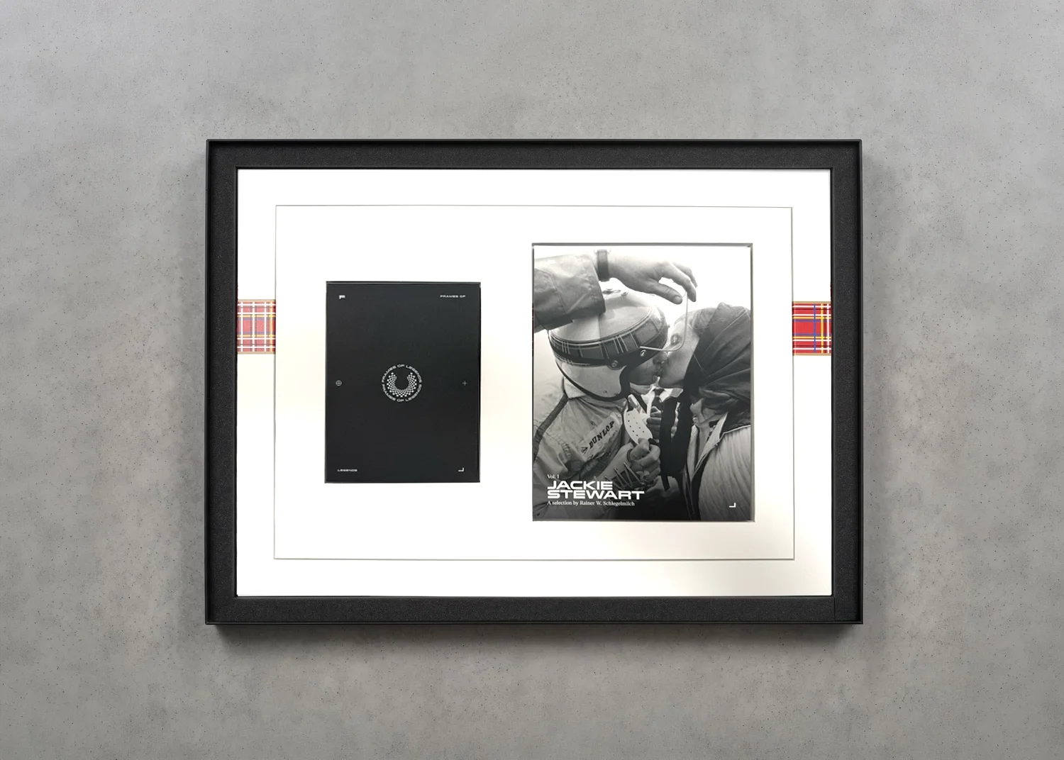 Framed black-and-white photo with a racing helmeted person and another person close in a kiss, with a poster reading Jackie Stewart and a black rectangular object on a white background.