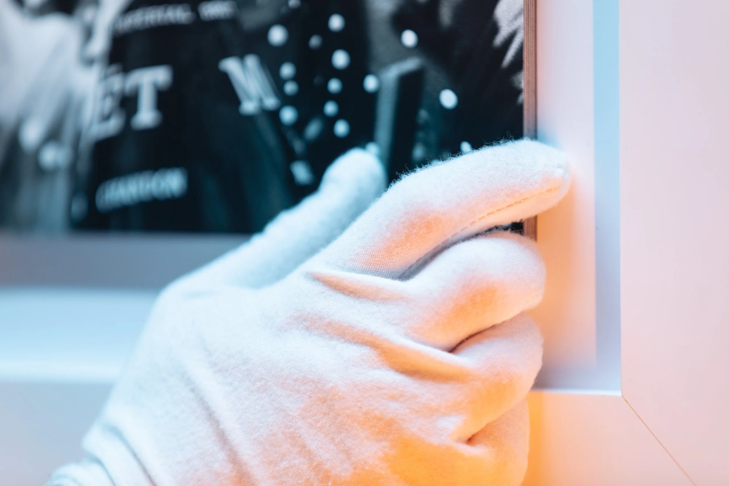 A gloved hand holds a black circuit board with white markings and components.