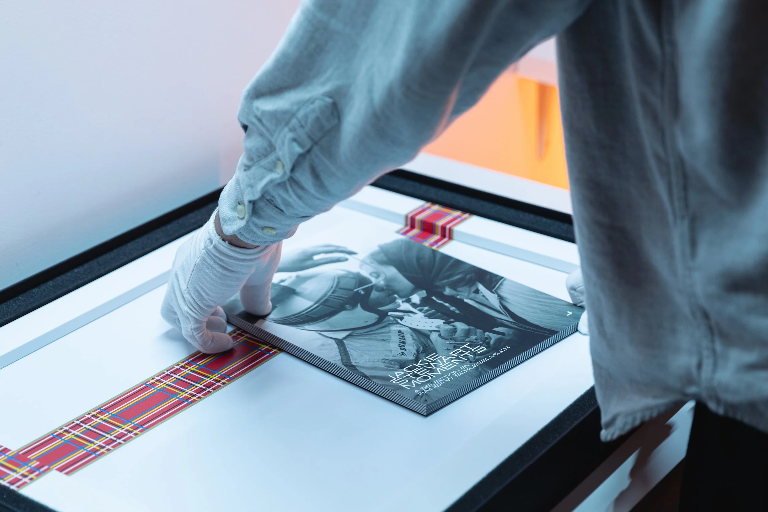 Person with gloves handling a magazine inside a lightbox display.