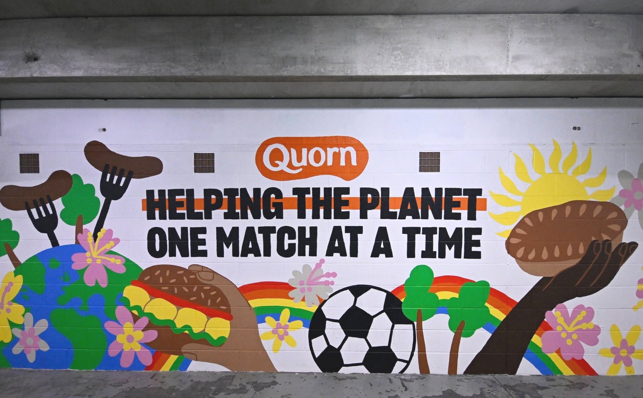 Mural at a Liverpool FC stadium promoting sustainability and healthy eating with the message “Helping the planet one match at a time.”