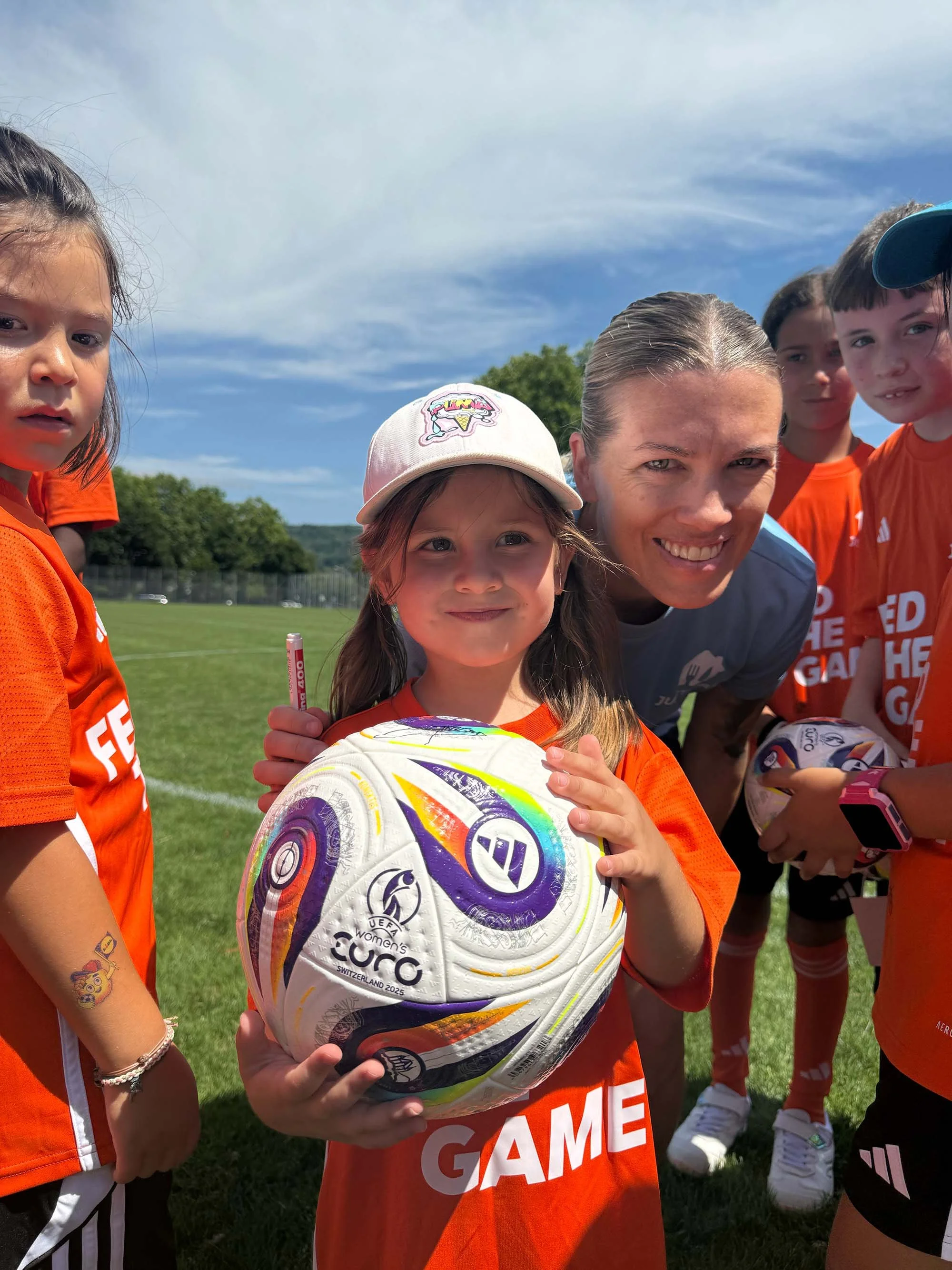 Lara Dickenmann hugs a young girl as they smile at the camera at a Feed the Game camp. 