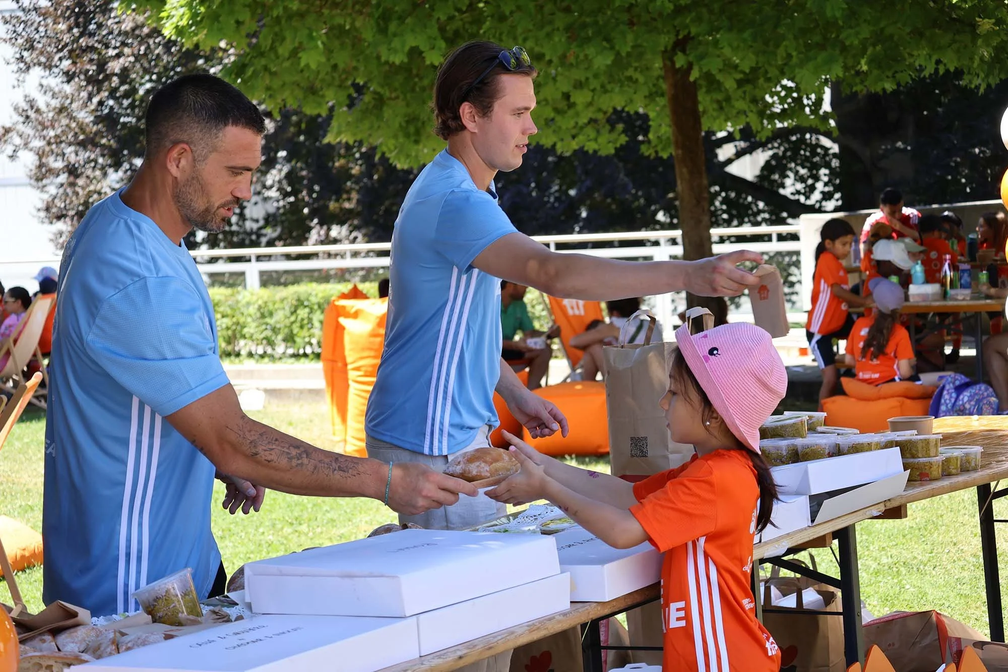 A young girl receives food from Feed the Game staff at a serving table.