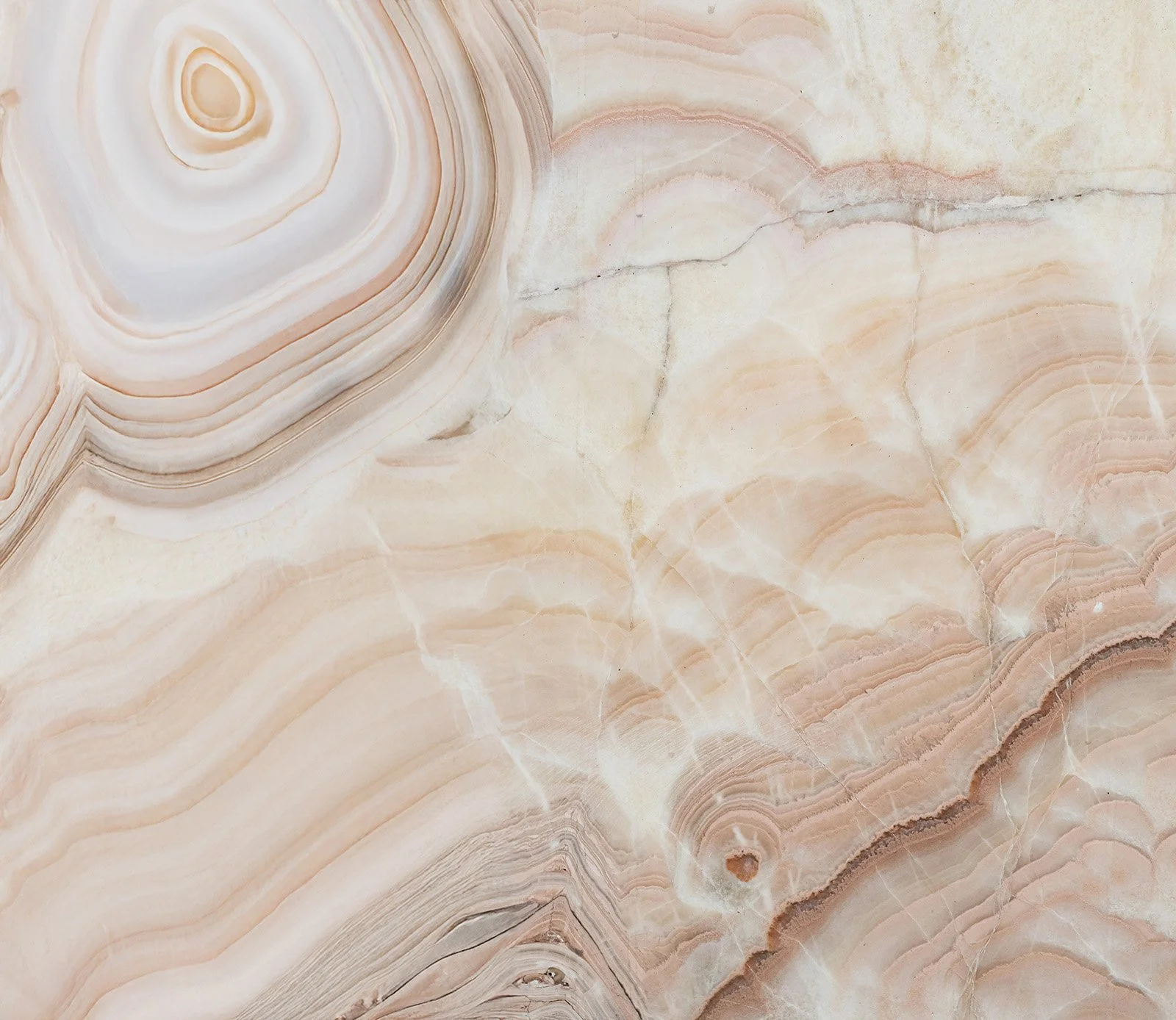 Close-up of a polished marble surface with natural patterns and veins in shades of cream, beige, and light brown.