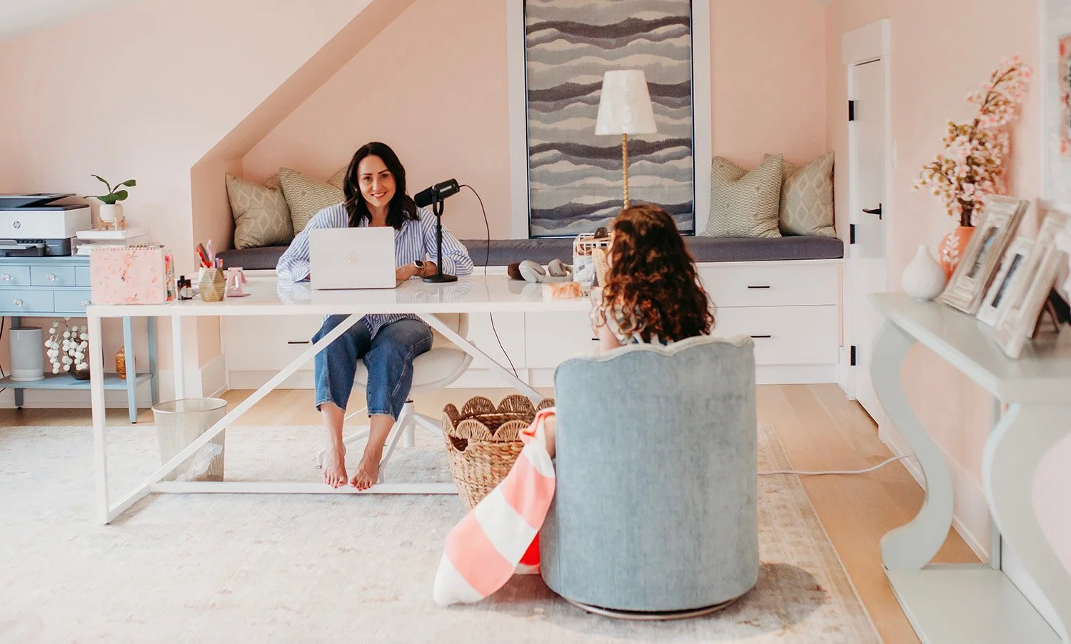 Woman recording a podcast in a cozy, well-decorated room with a young girl sitting across from her.