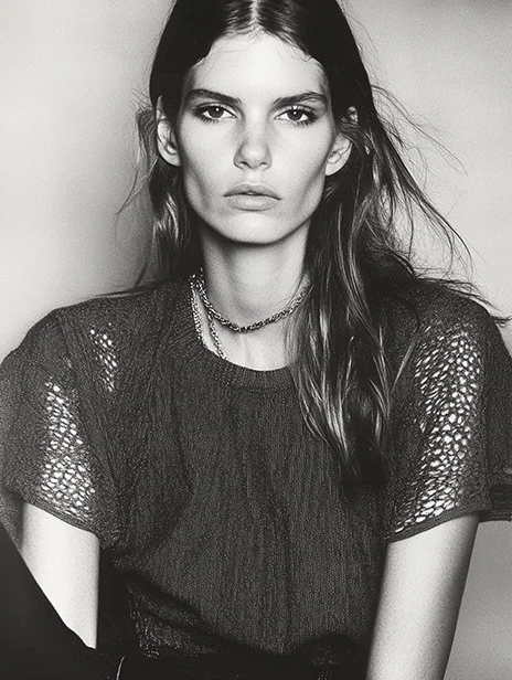 Black and white portrait of a woman with long, loose hair, wearing a textured short-sleeve top and layered necklaces, looking directly at the camera. Ai Generated, Creative direction with  AI 