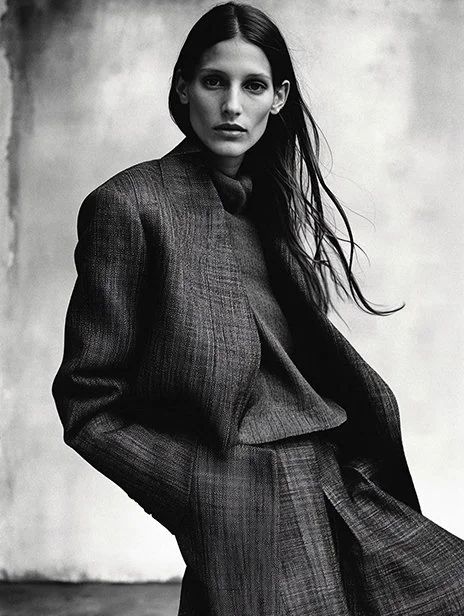 Black and white photo of a woman with long hair wearing a dark plaid suit, standing against a plain background. Ai Generated, Creative direction with  AI 