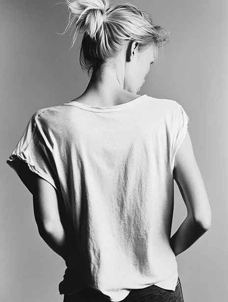 Black and white photo of a woman with her hair in a messy bun, wearing a loose-fitting t-shirt, turned slightly away from the camera. Ai Generated, Creative direction with  AI 