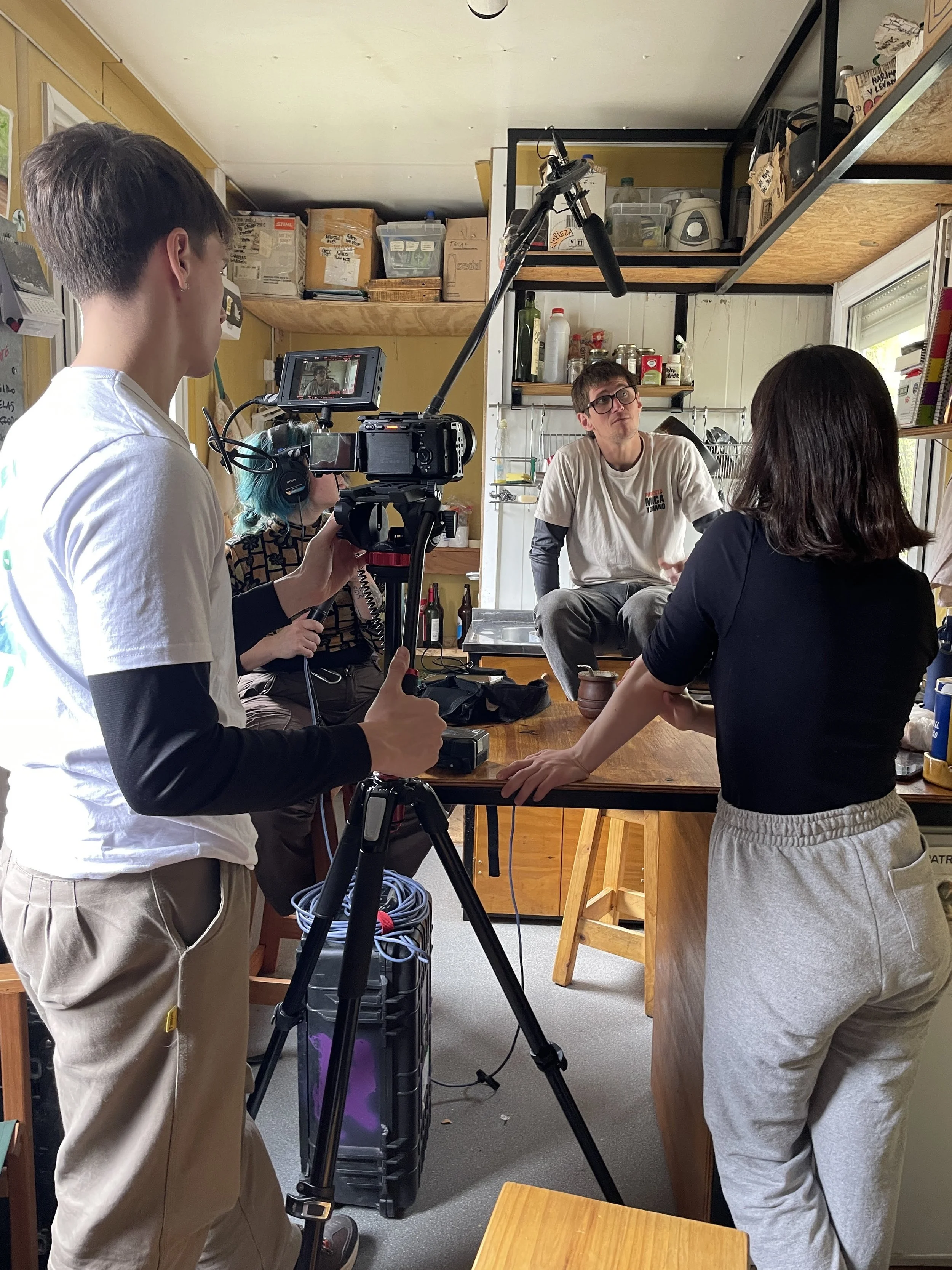 Equipo de filmación grabando a un hombre sentado en una cocina}}}