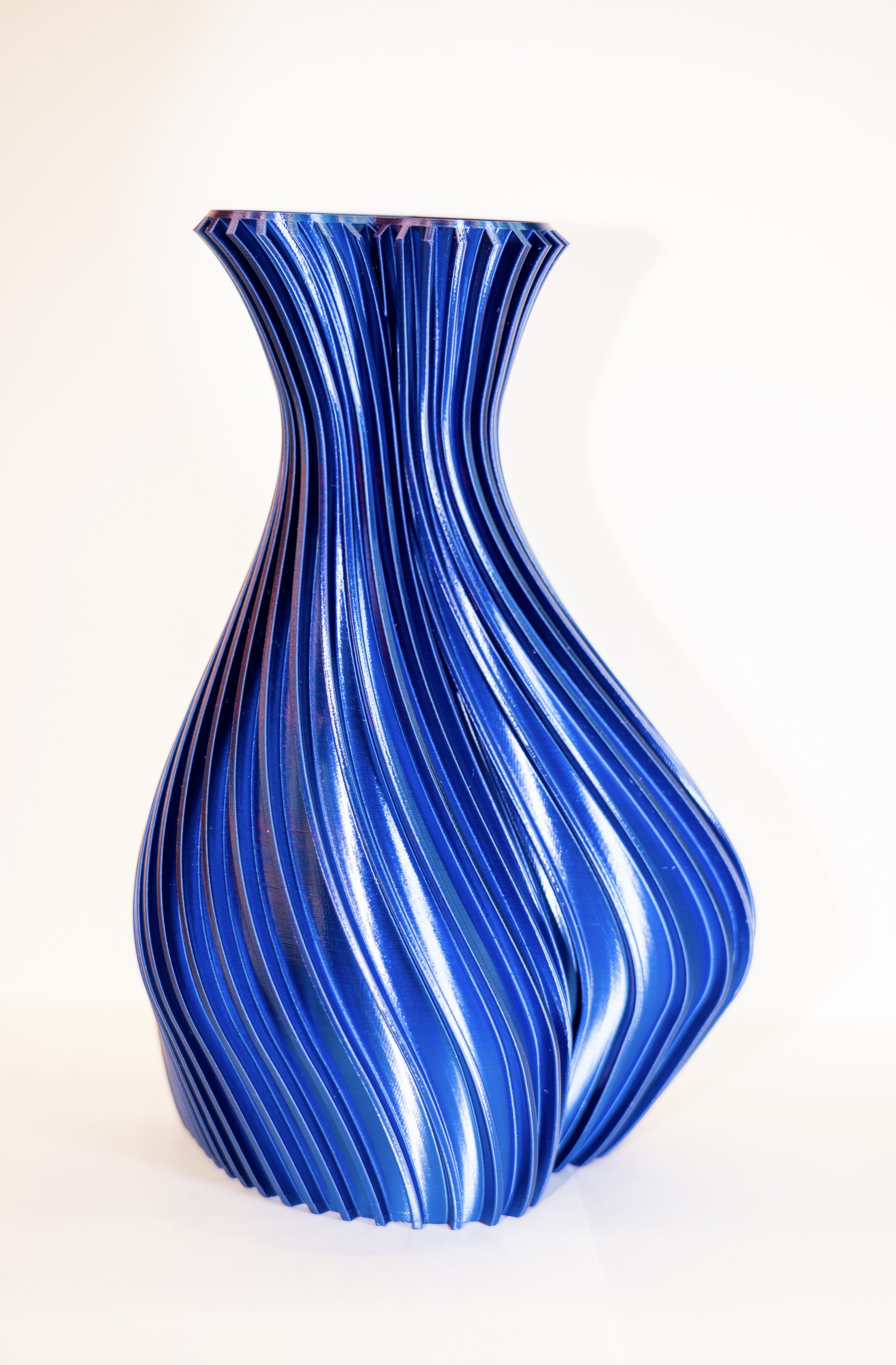 A blue, twisted glass vase with a ribbed texture and a sleek, modern design.
