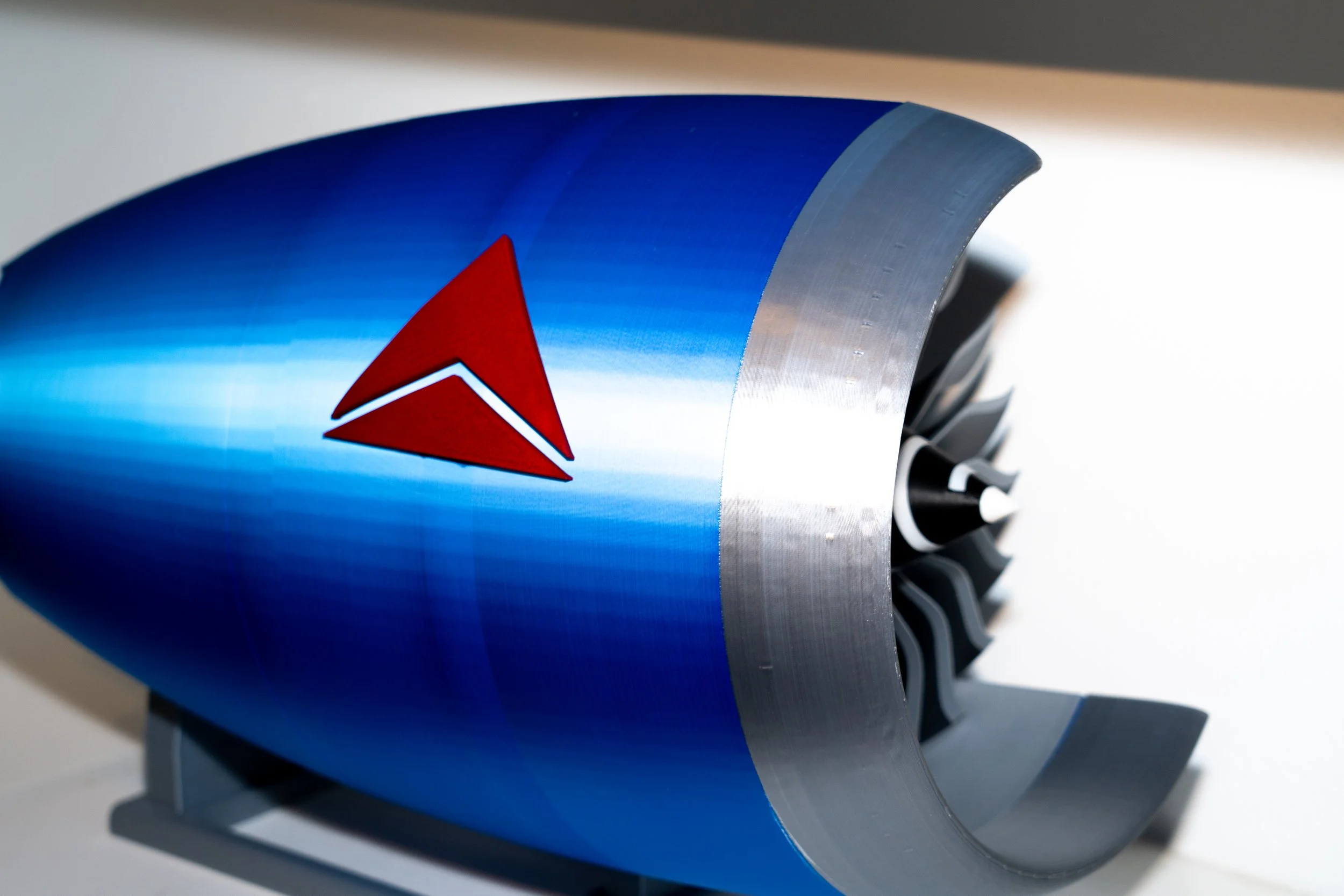 Close-up of a submarine's front with a blue exterior and a red and white emblem, and visible propellers.