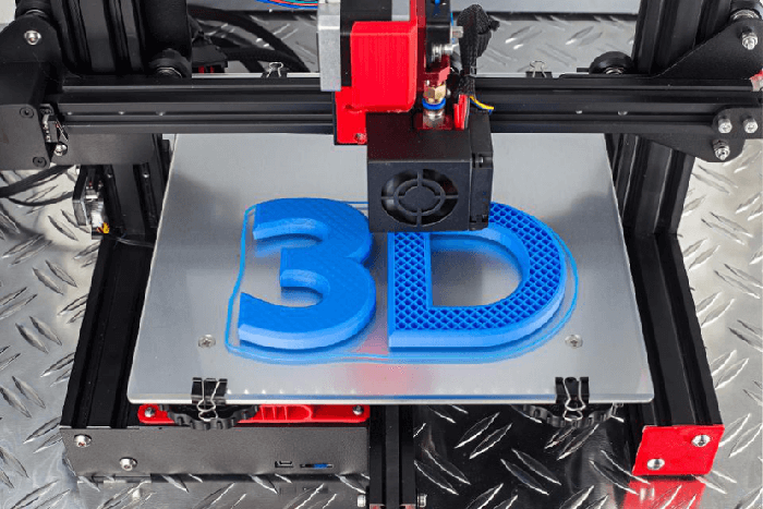 A 3D printer printing a blue '3D' design on a metallic print bed.